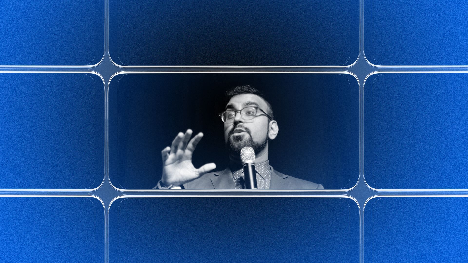 A black-and-white photo of Rohit Malhotra speaking into a microphone and gesturing with his hands