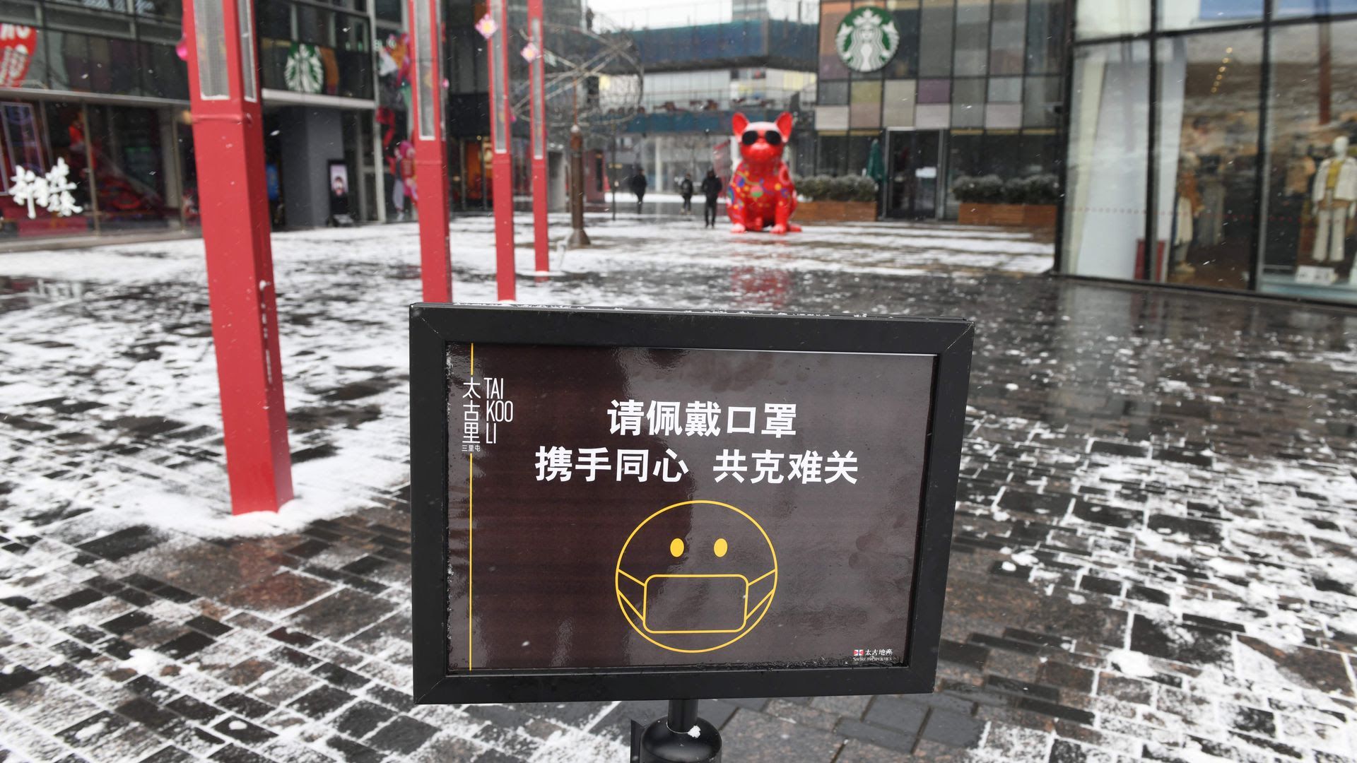 A sign urges visitors to wear face masks at the entrance to an empty shopping mall in Beijing