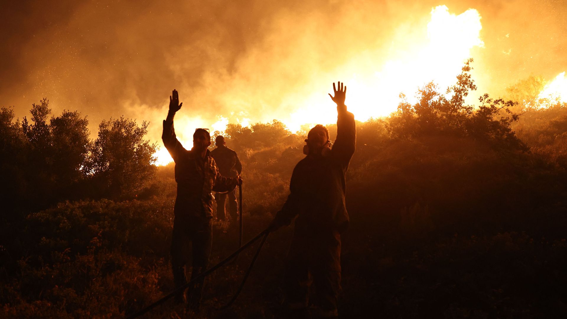 Firefighters gestures as they work to extinguish a wild fire in Drafi agglomeration, north of Athens, on July 19.