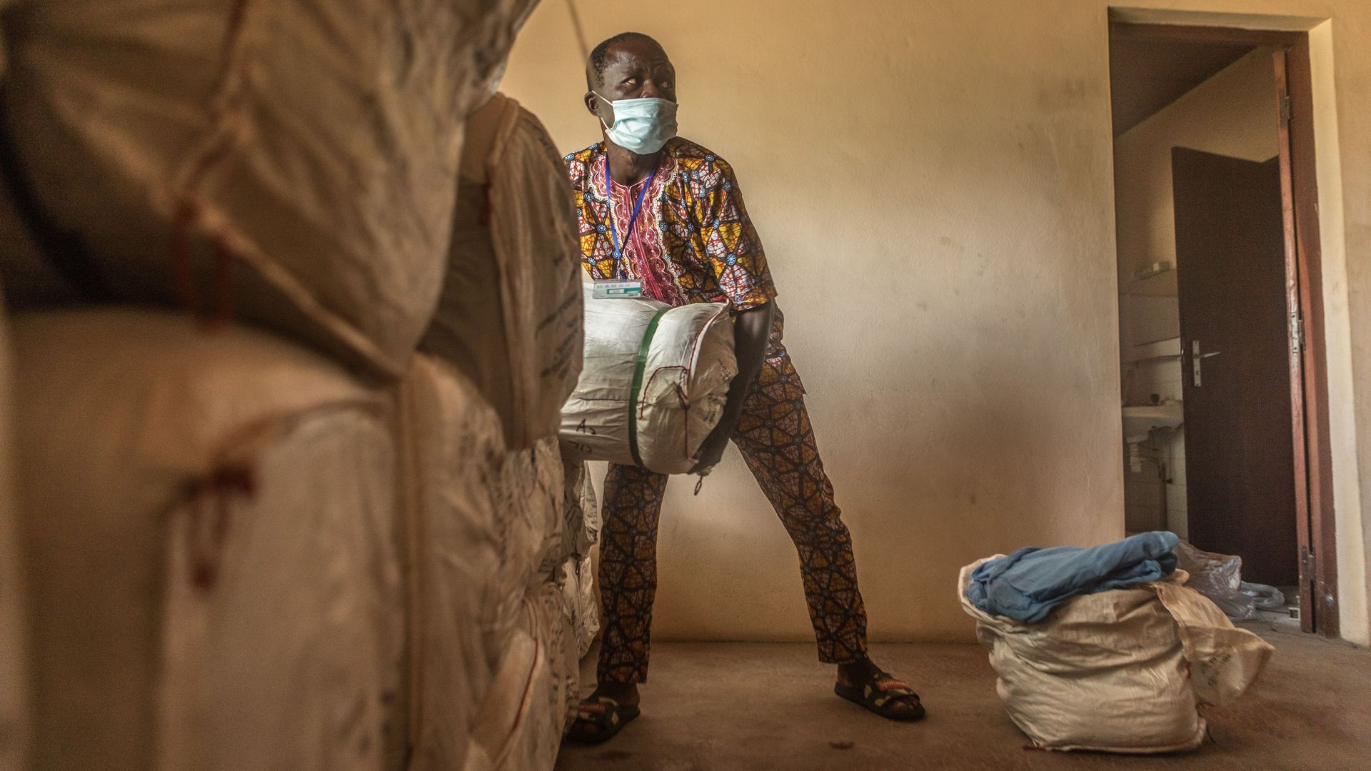 In this image, a man carries mosquito nets