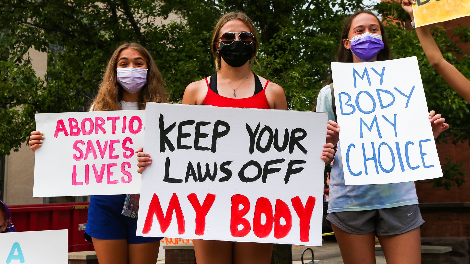 Picture of three people holding signs in support of abortion rights
