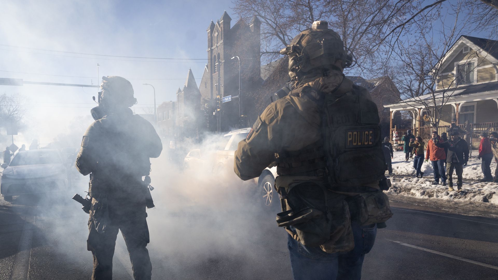 Federal agents and Minneapolis residents confront each other on a street filled with tear gas during protests against federal immigration enforcement.