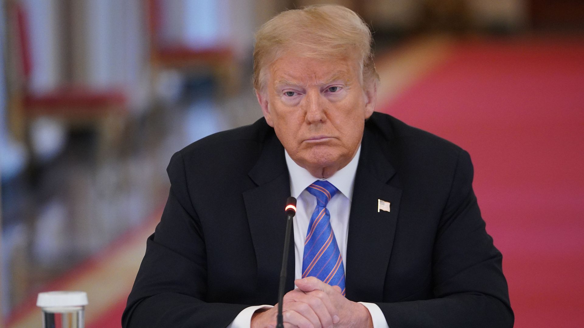 President Donald Trump sits in a chair wearing a tie 