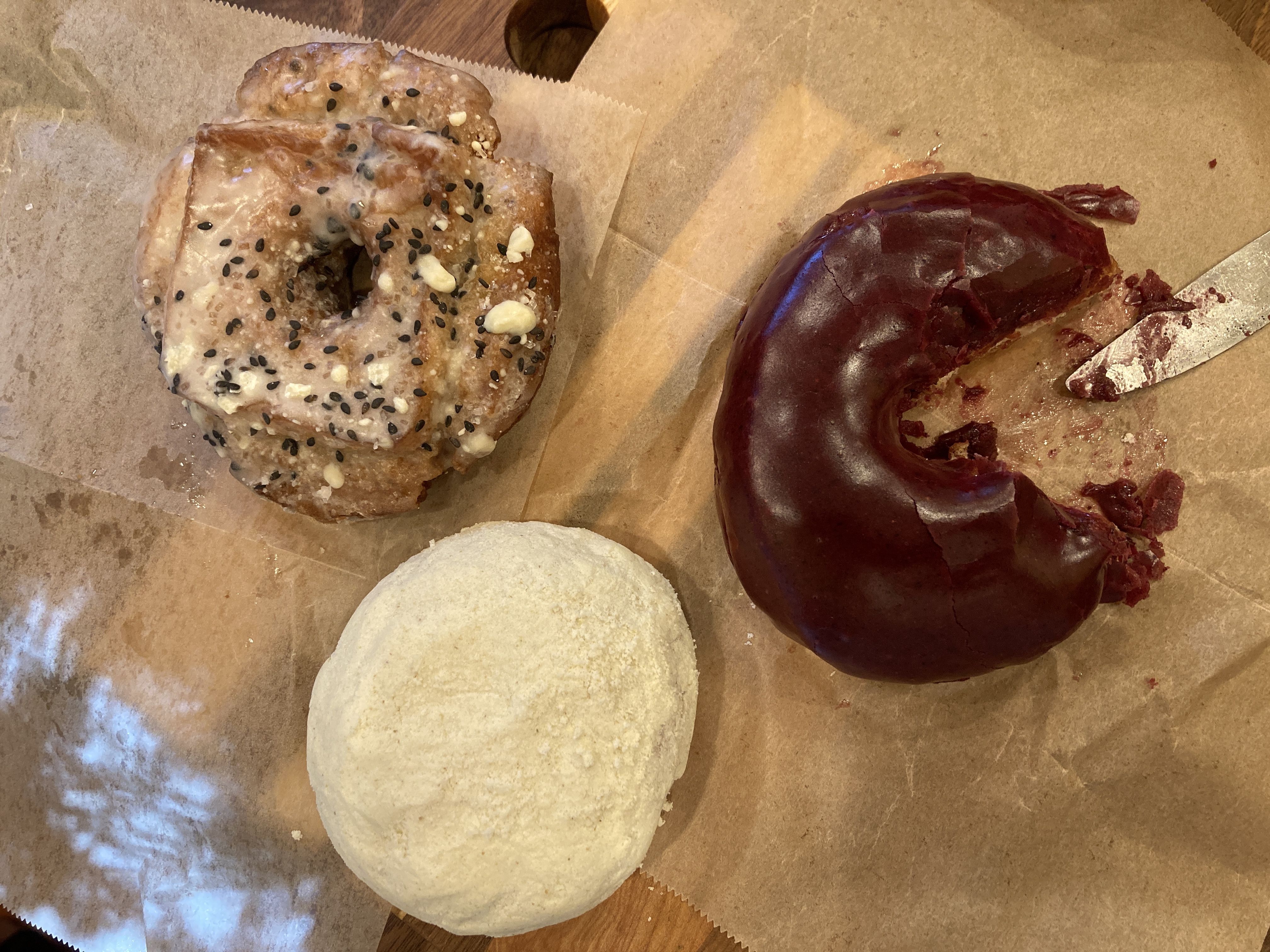 Three doughnuts on a wooden cutting board.