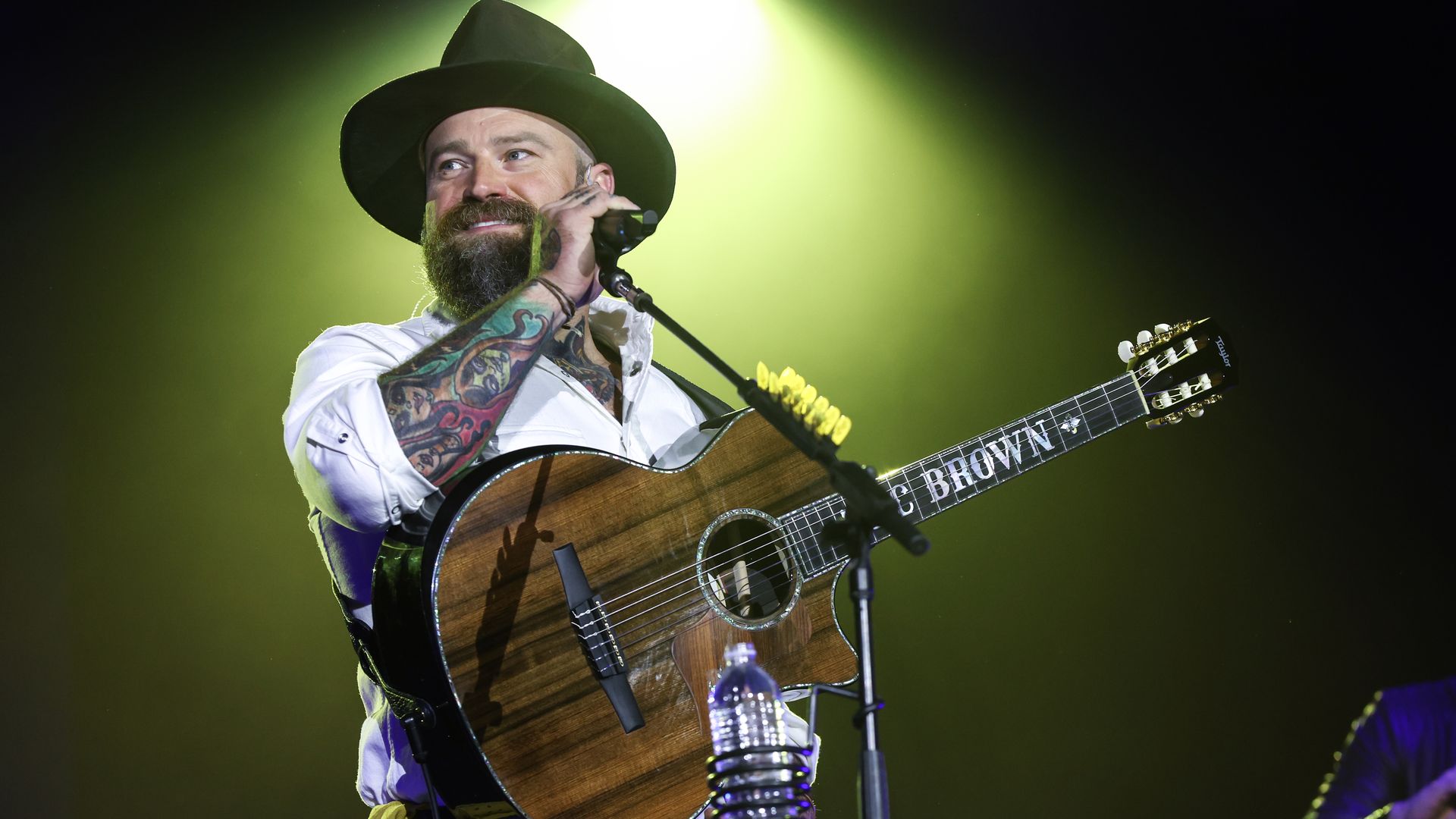 Zac Brown of the Zac Brown Band on stage holding a guitar in front of a microphone. 