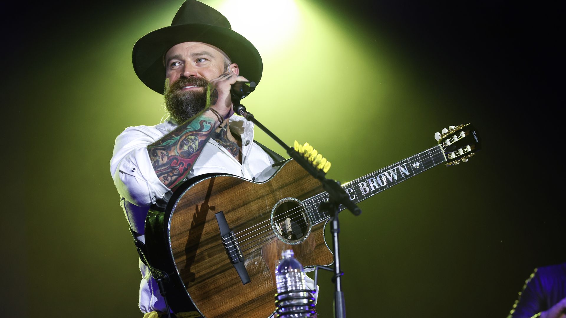 Zac Brown of the Zac Brown Band on stage holding a guitar in front of a microphone.