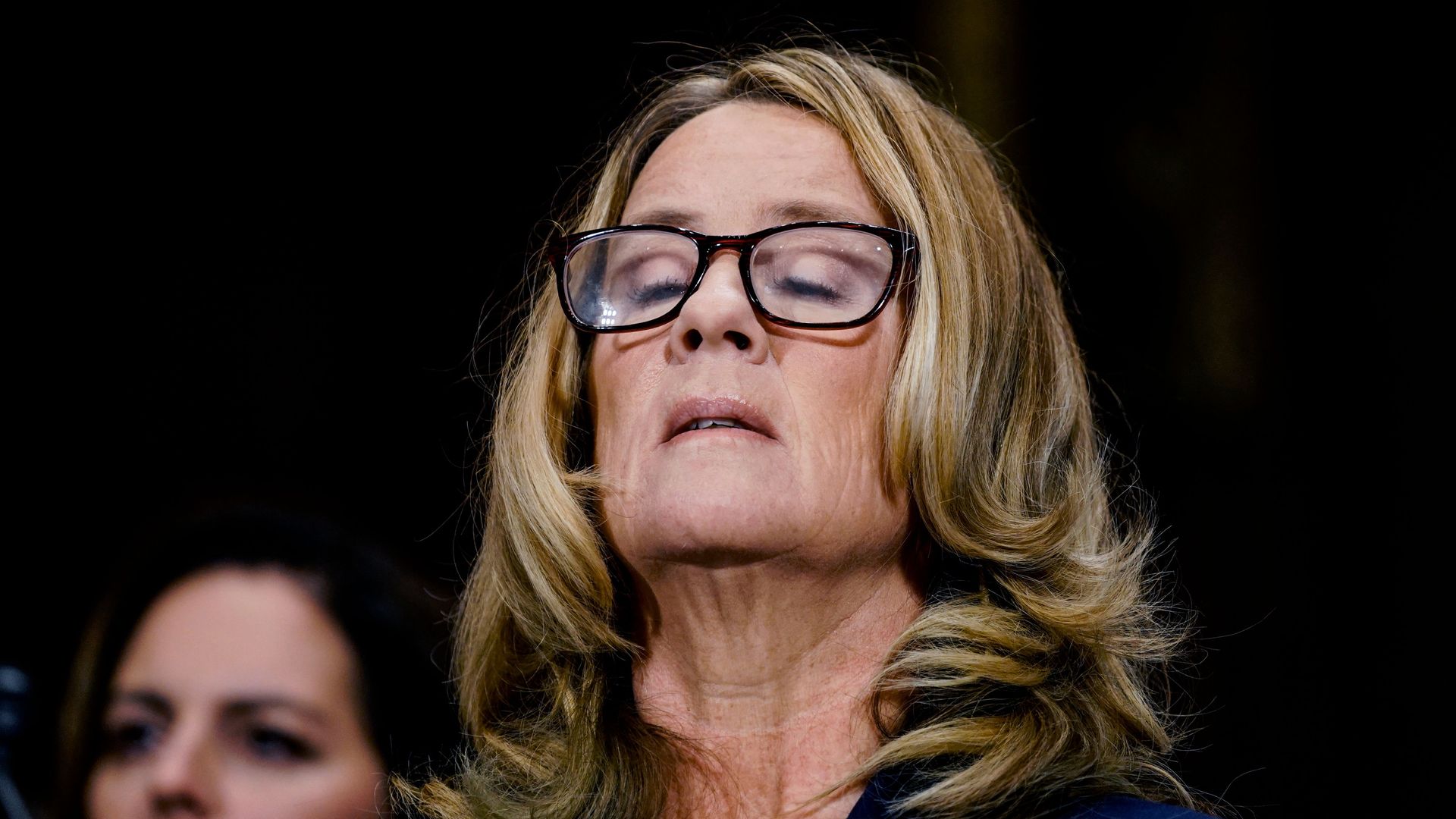 Dr. Christine Blasey Ford closes eyes and lifts head to sky.