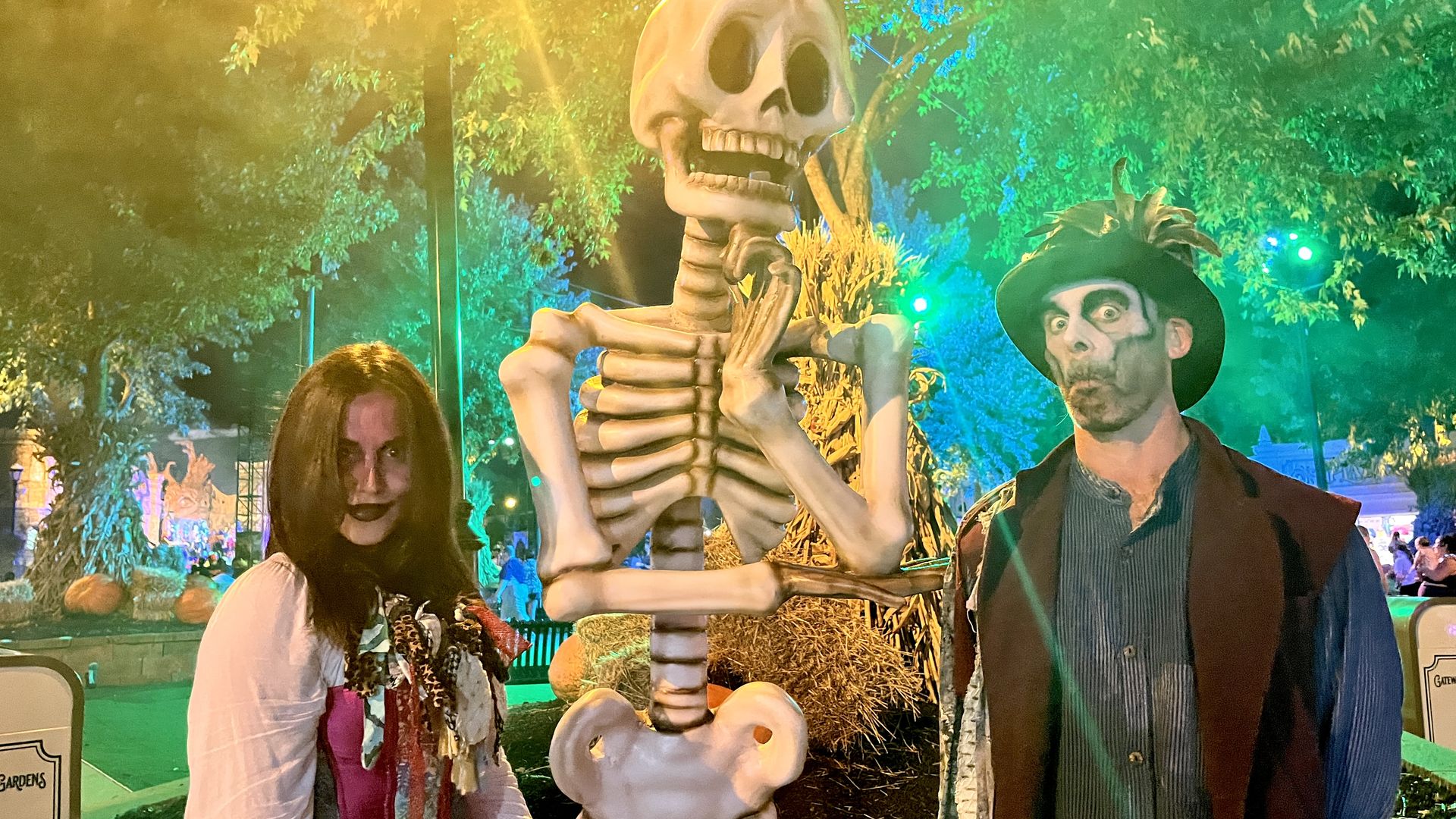 Axios Kansas City reporters Abbey and Travis in Halloween costumes pose beside a large skeleton prop at Worlds of Fun's Halloween Haunt.