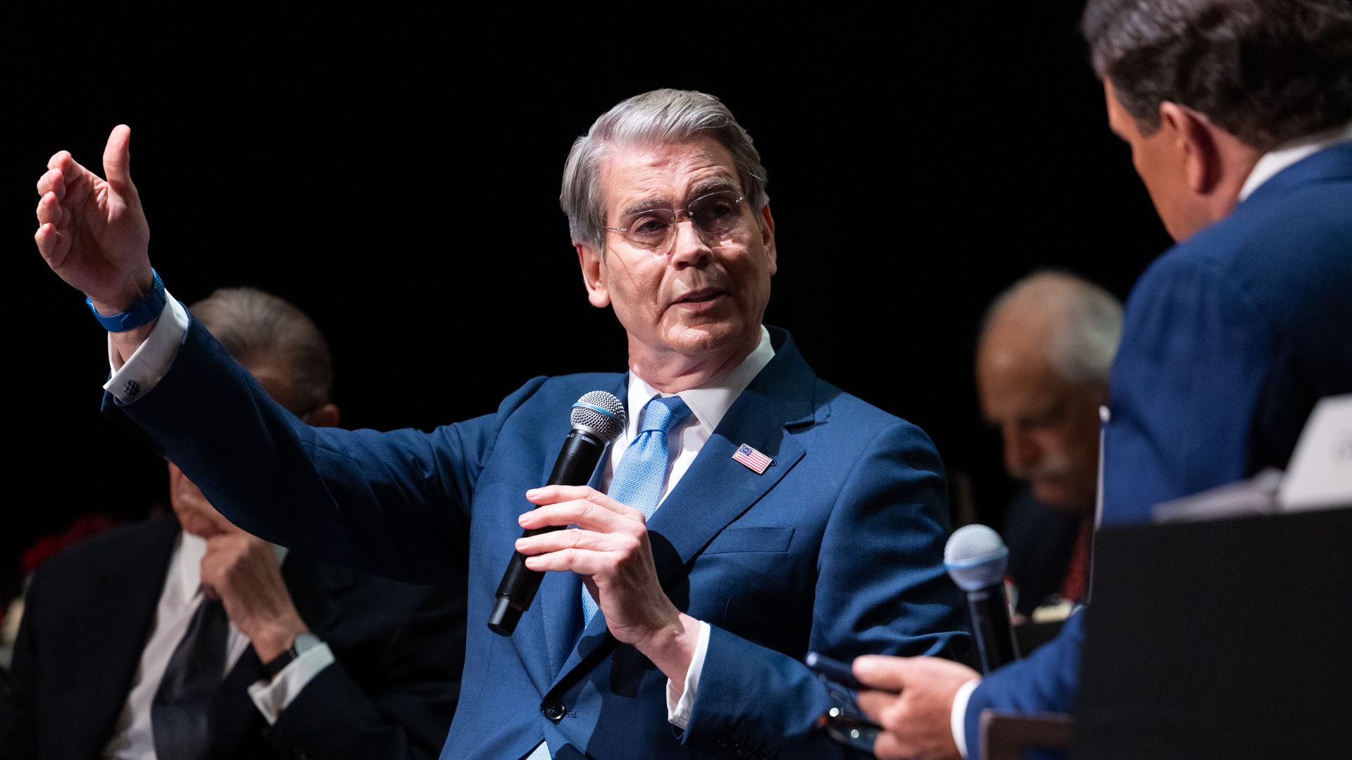 Treasury Secretary Scott Bessent holding a mic and gesturing with his right hand.