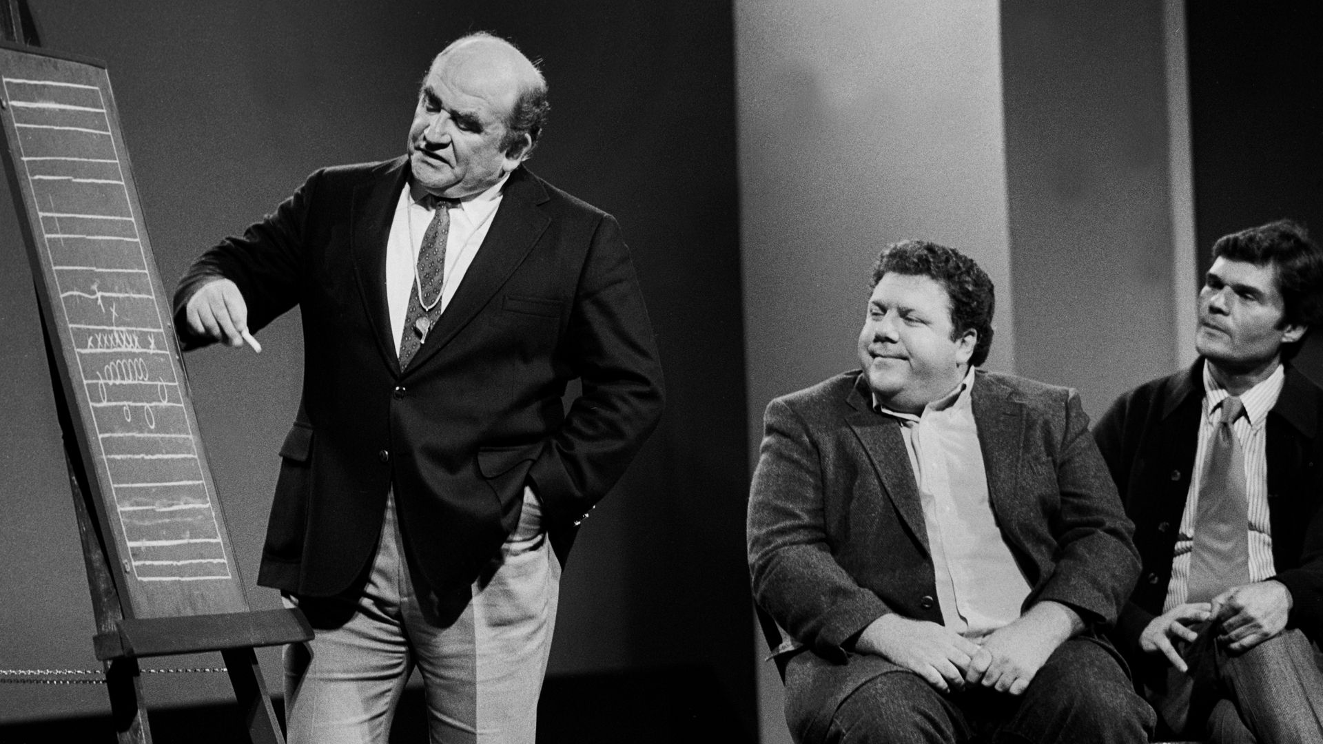 Photo of three actors on a stage performing a skit. 
