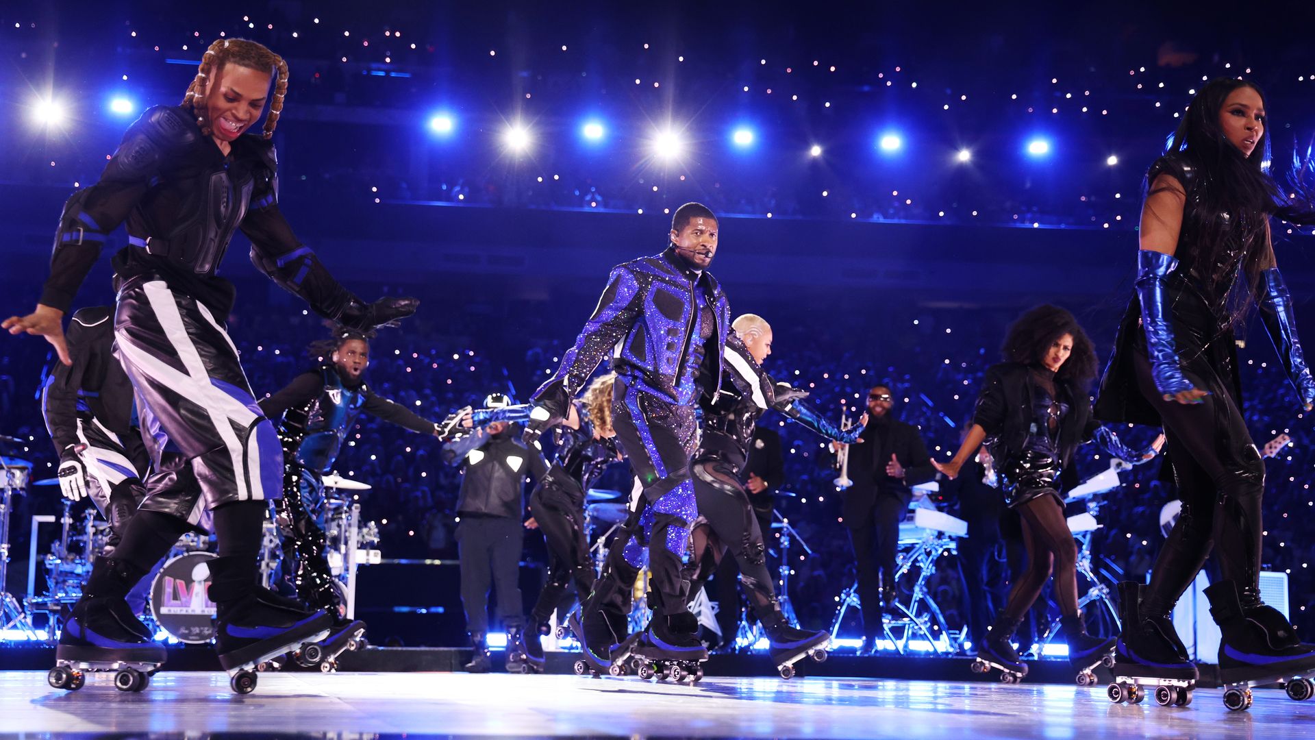 Dancers wear roller skates on a brightly-lit stage with spotlights in the background