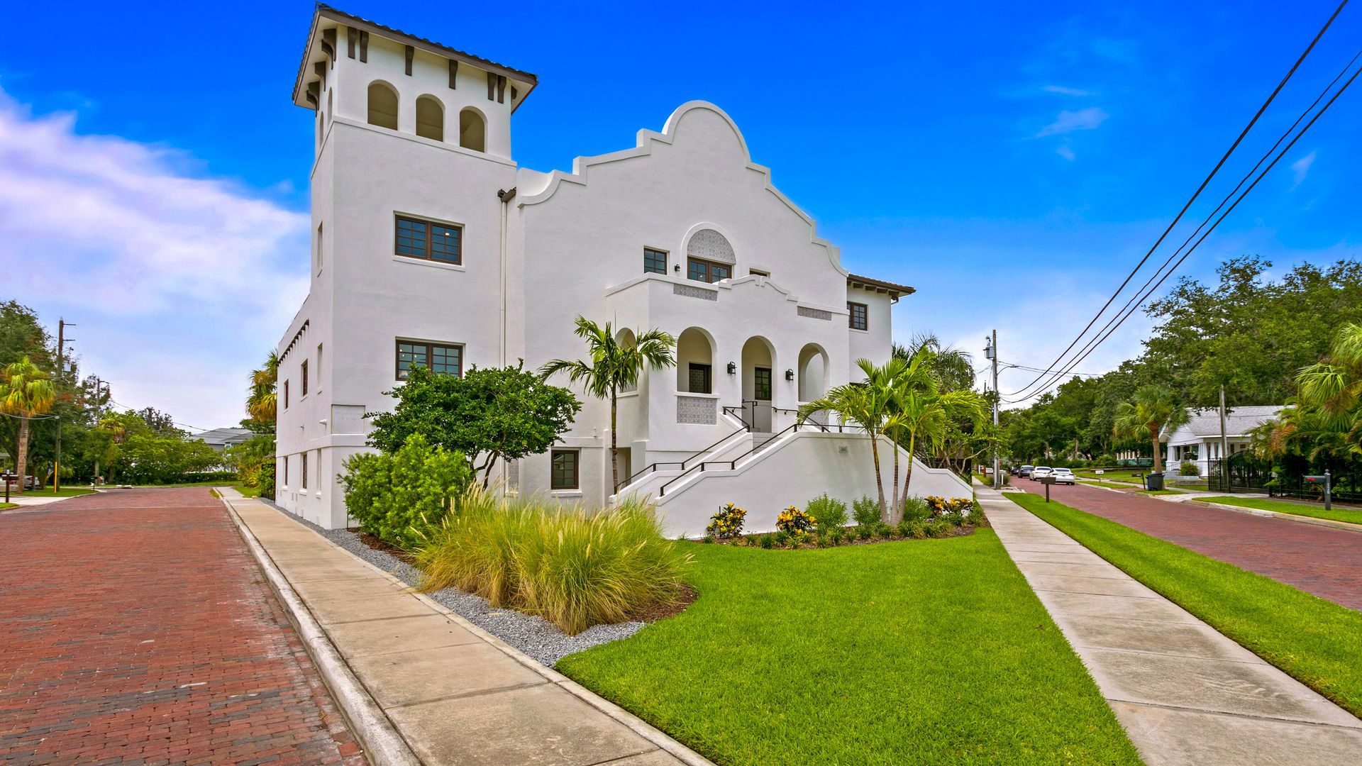 A Mission-style, cream-colored home with a manicured green lawn in front. 