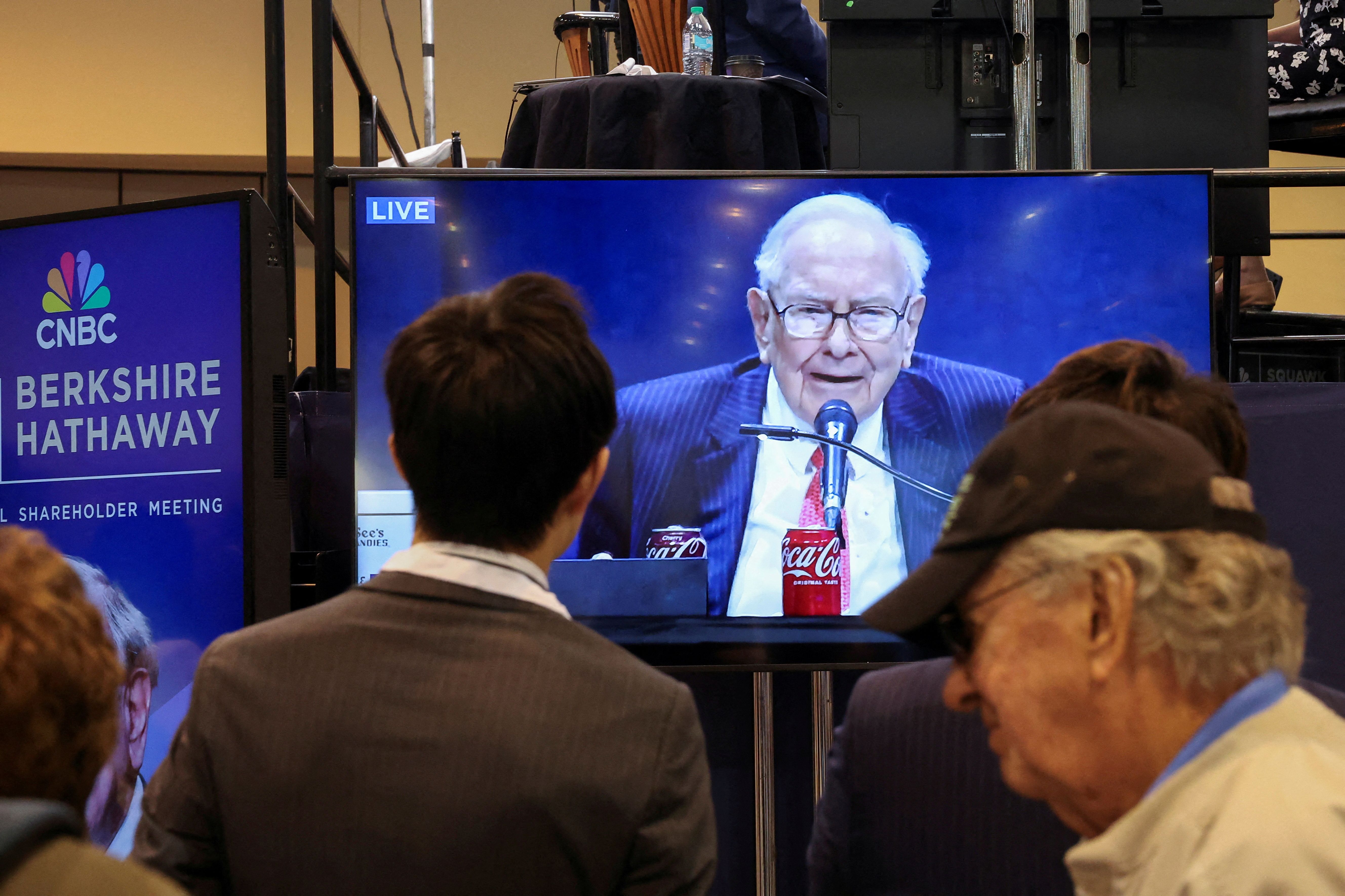 People watch as Berkshire Hathaway chairman Warren Buffett is seen on a screen speaking at the Berkshire Hathaway Inc annual shareholders' meeting, in Omaha, Nebraska, U.S., May 3, 2025. REUTERS/Brendan McDermid 