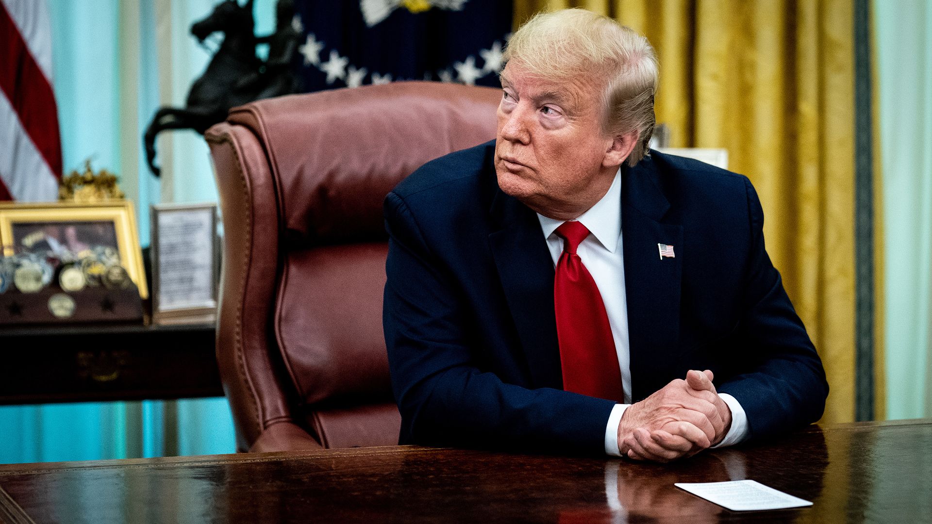 In this image, Trump sits at a desk