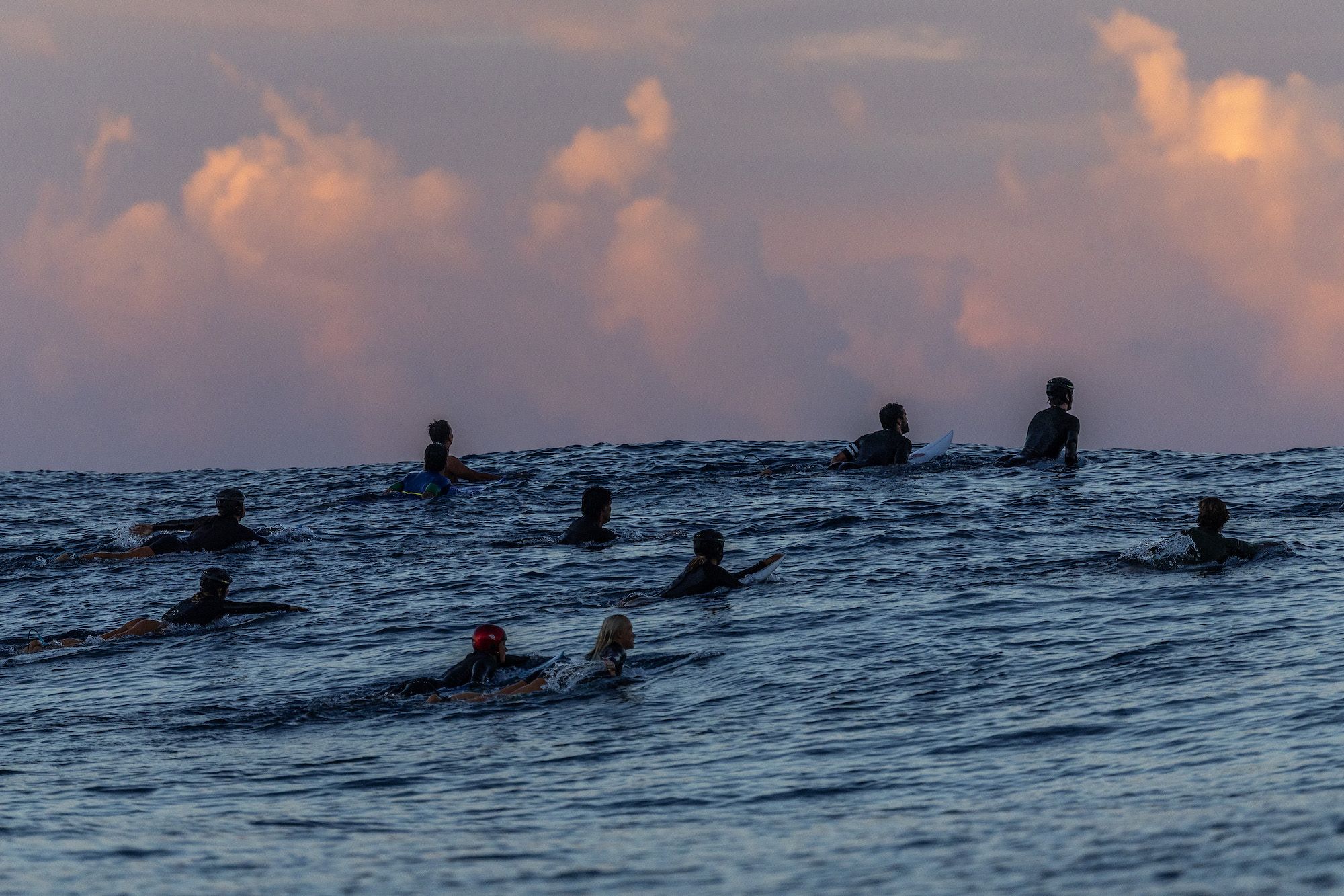 Surfers on the water at sunset.