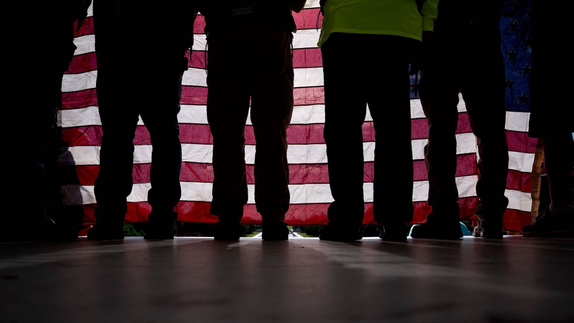 A group of veterans stand behind an American flag. 