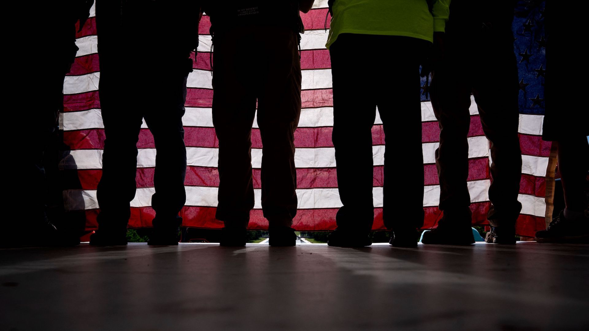 A group of veterans stand behind an American flag.