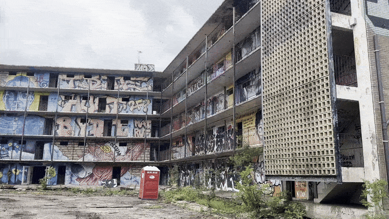 Video pans across a blighted apartment building complex covered with graffiti.