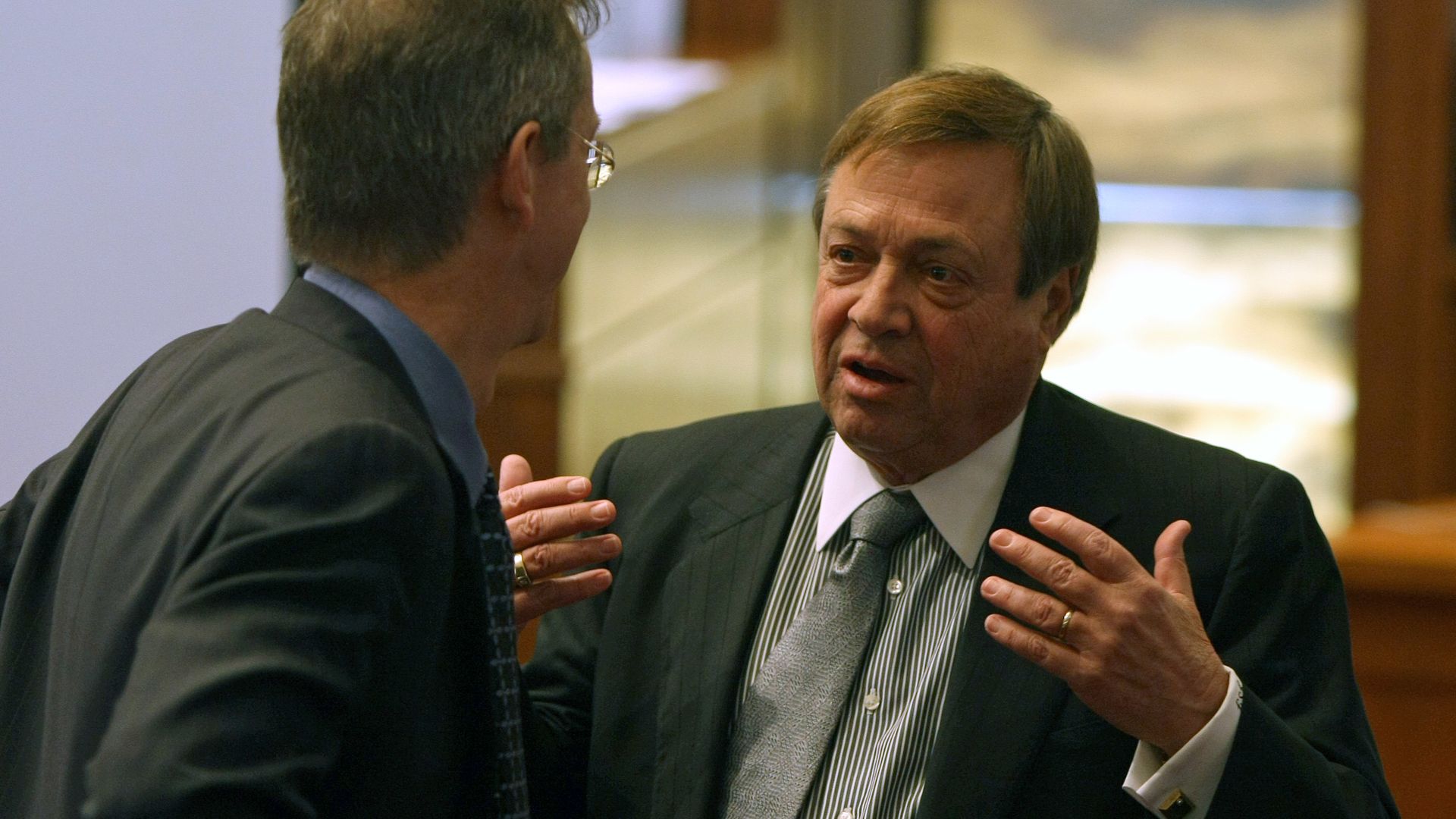 A man in a business suit speaks to another man