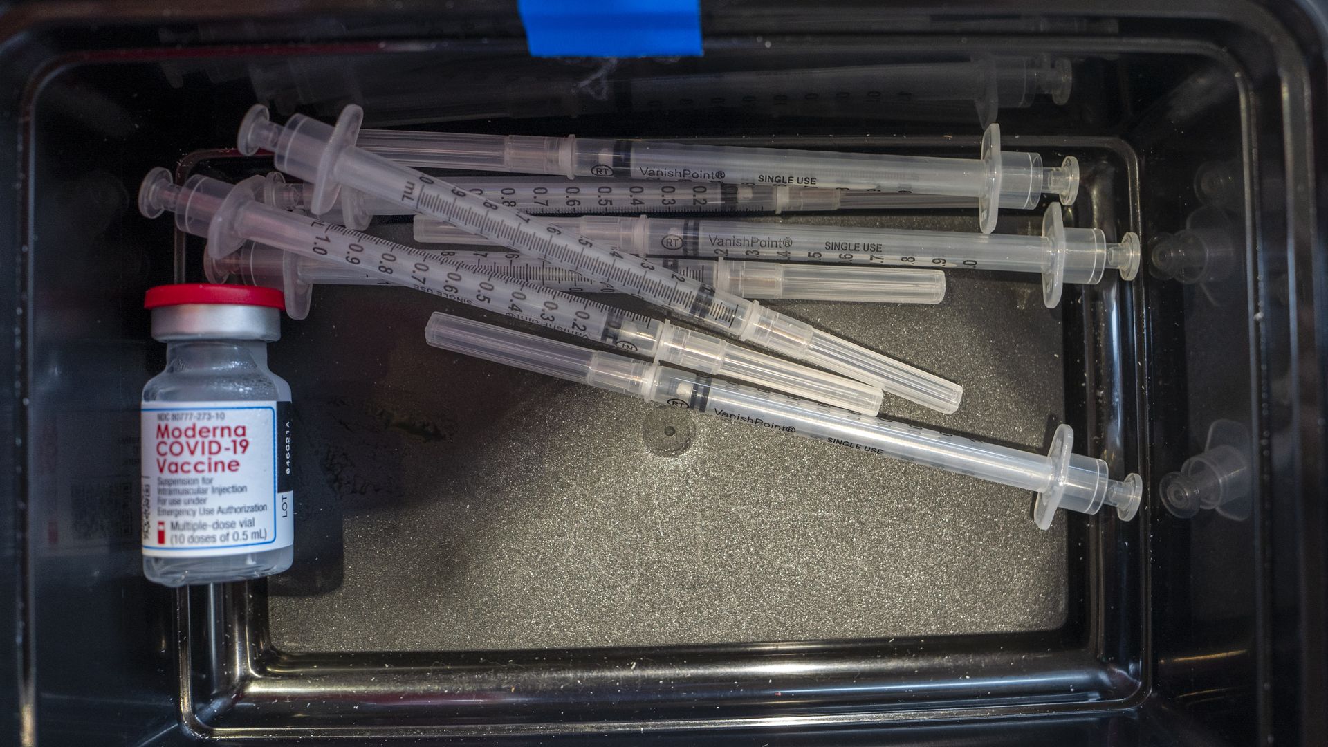 Photo of a box holding needles and a small bottle of the Moderna vaccine