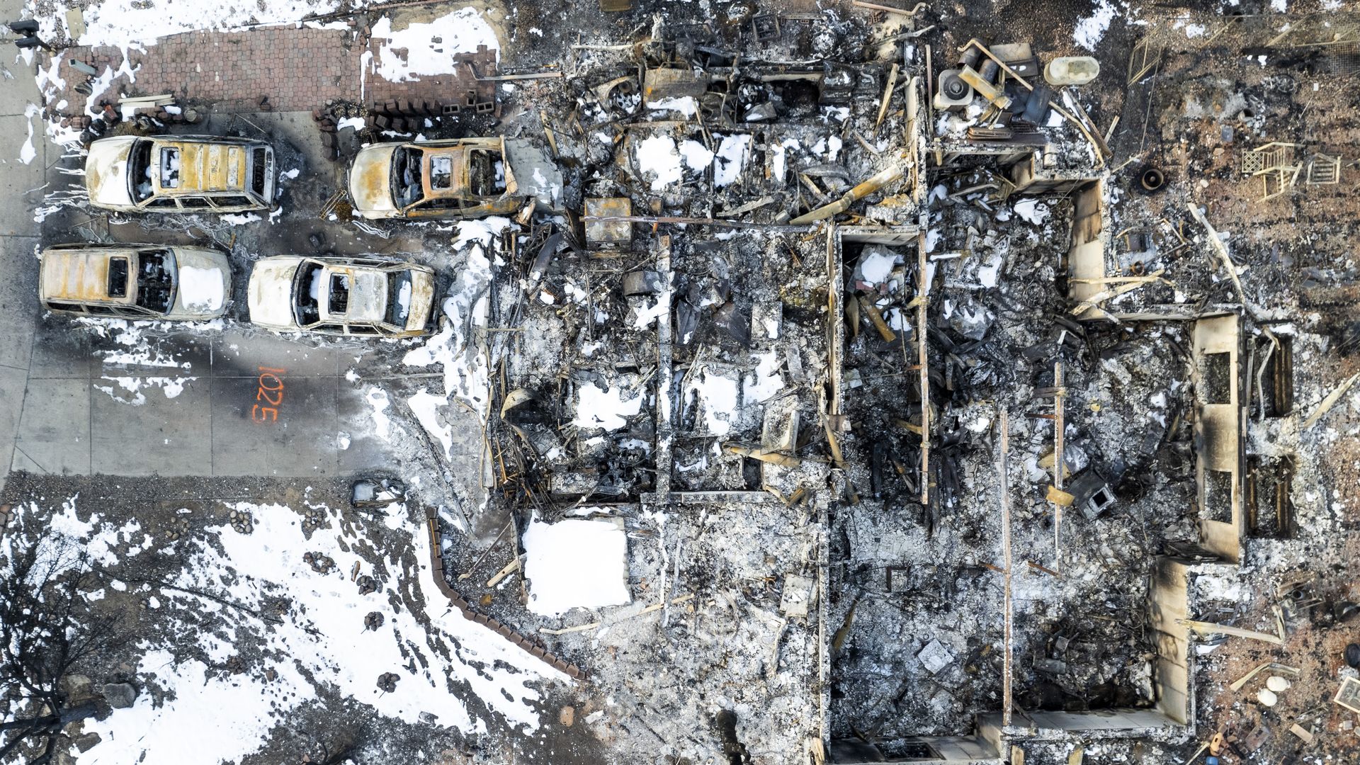 In this aerial view, burned cars sit in front of a home decimated by the Marshall Fire on January 4, 2022.