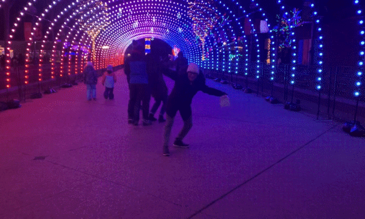 GIF of a woman dancing under Christmas lights. 