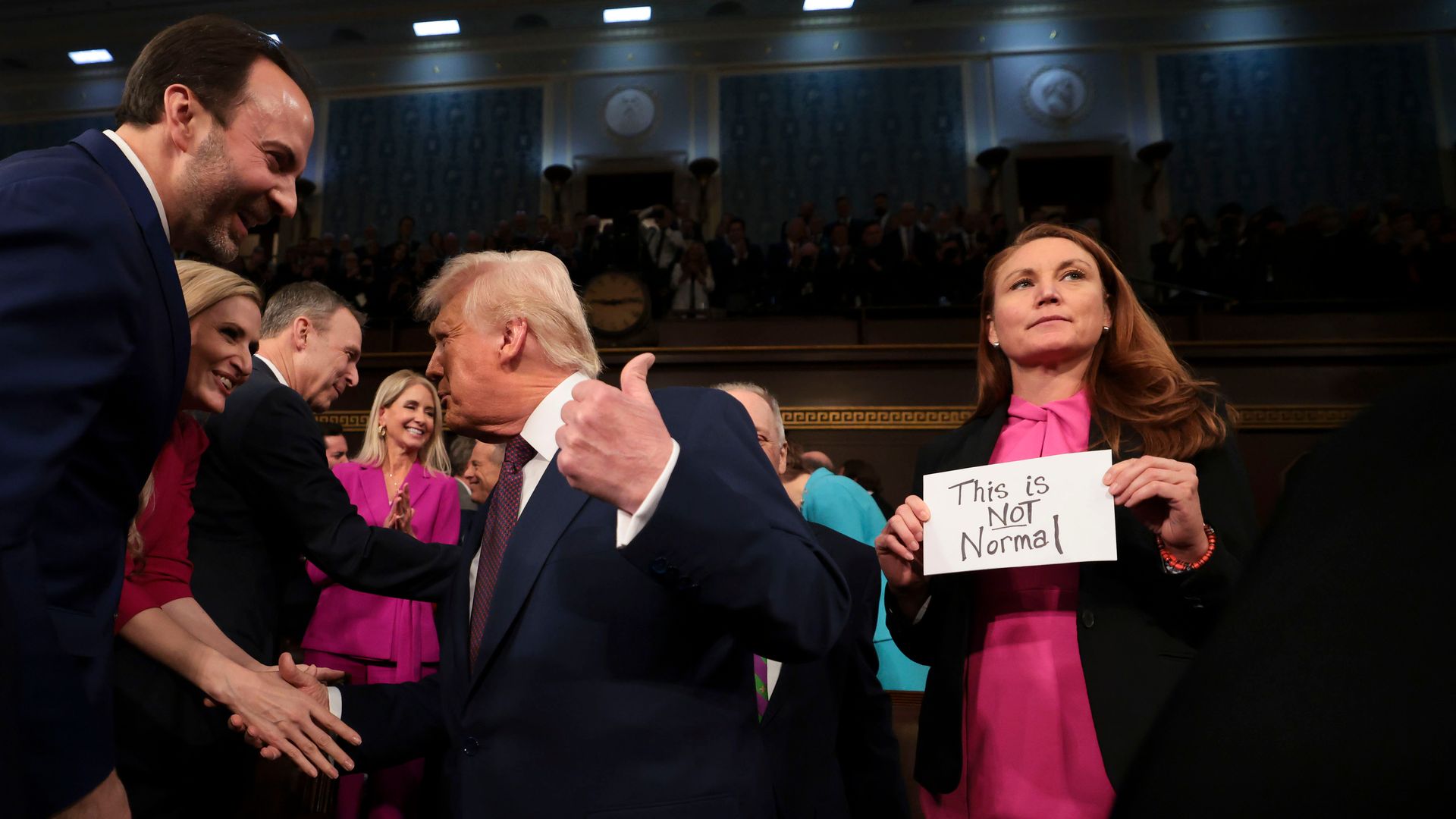  Rep. Melanie Stansbury (D-N.M.) holds a sign in protest as  President Trump arrives during a joint session of Congress in the House Chamber. 