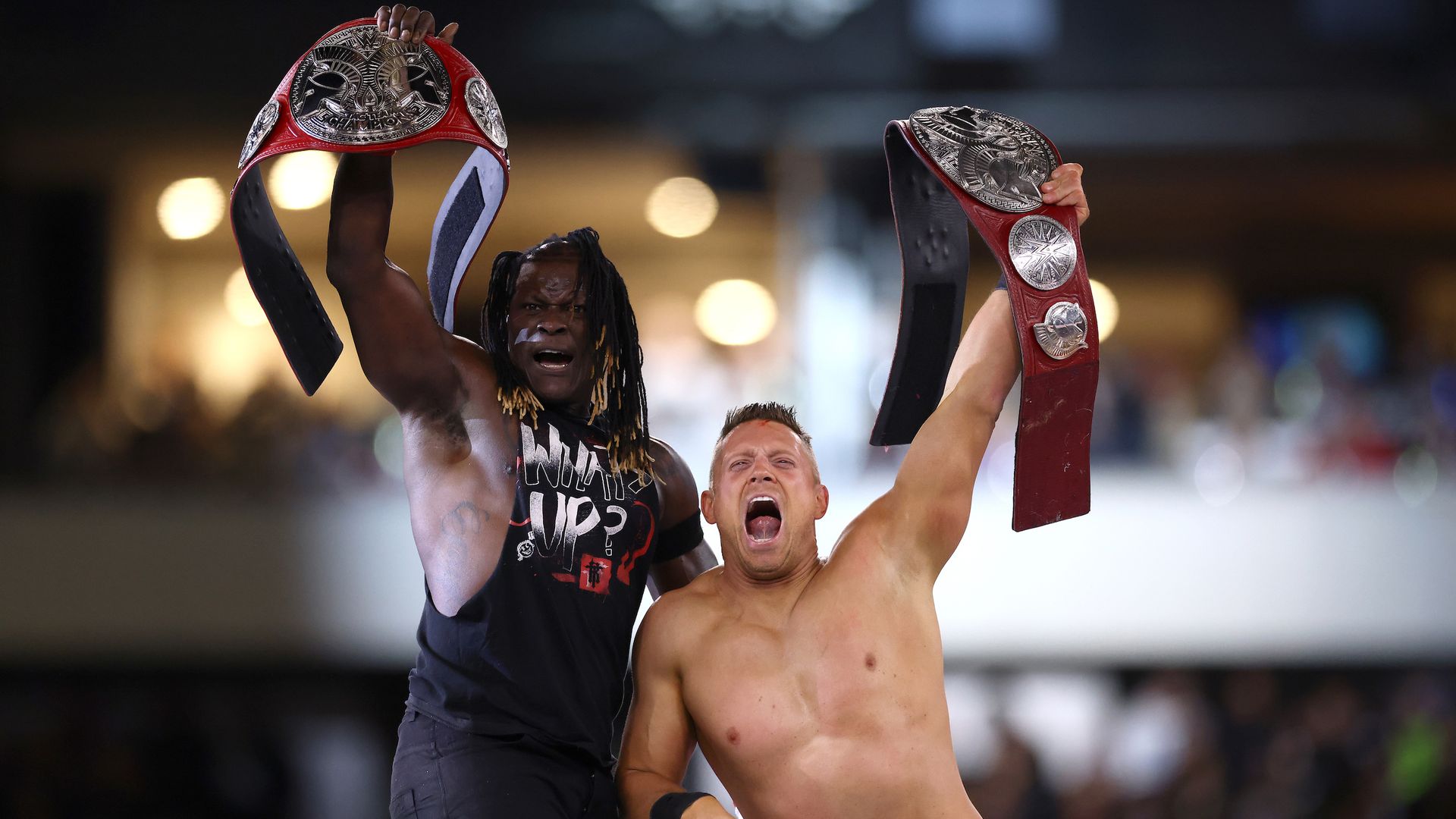 Two WWE wrestlers raise belts. 