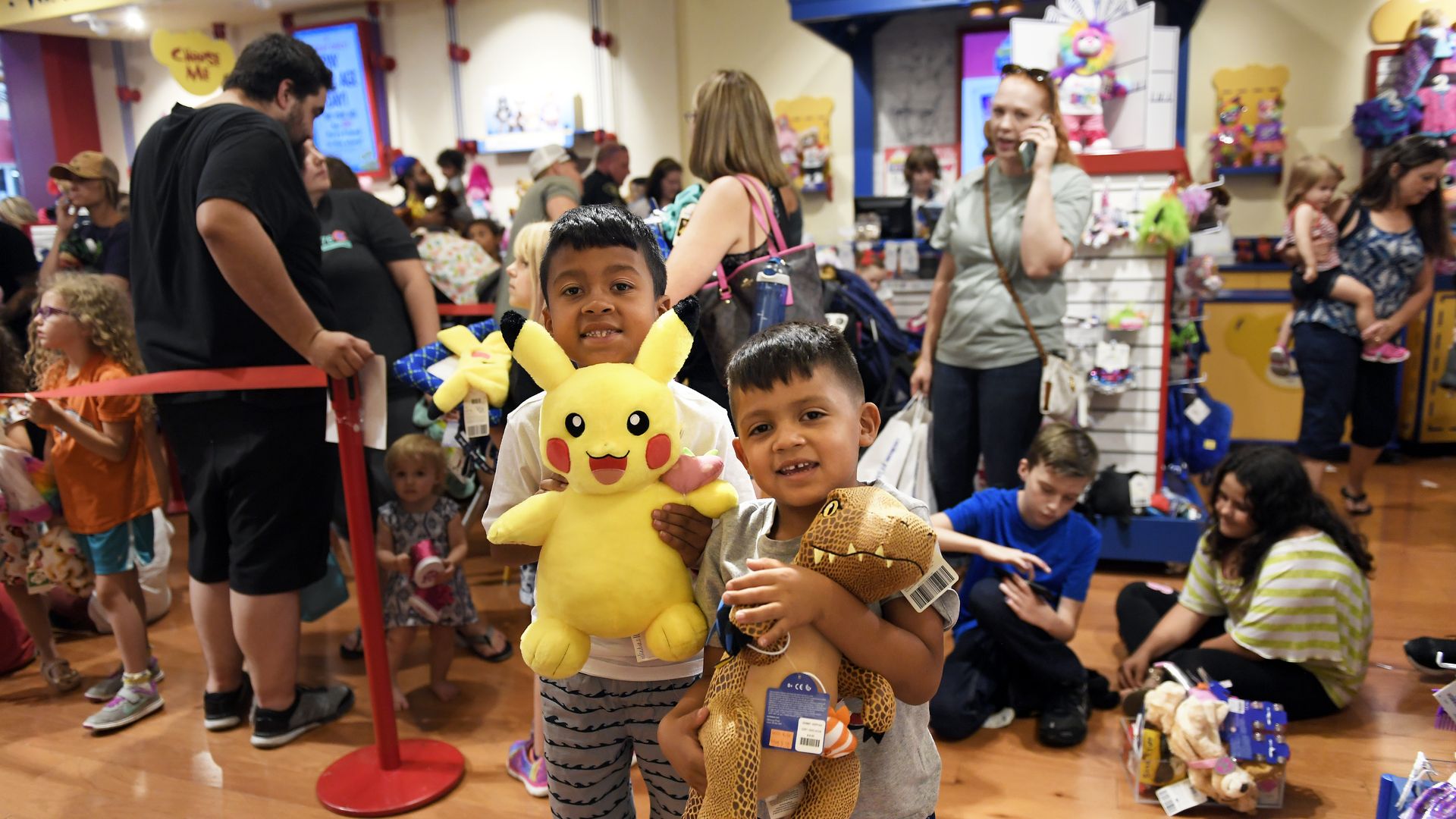 Two children pose with their plush toys at a Build-A-Bear store.