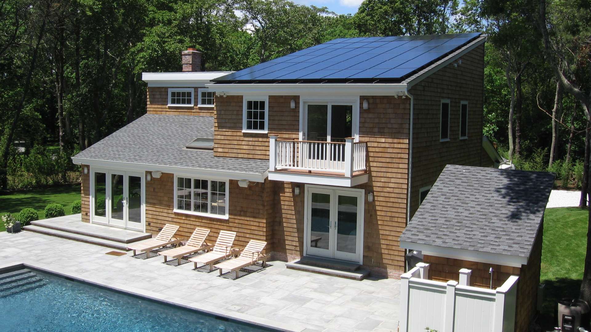 A brown house with a pool. There are solar panels on the roof. 