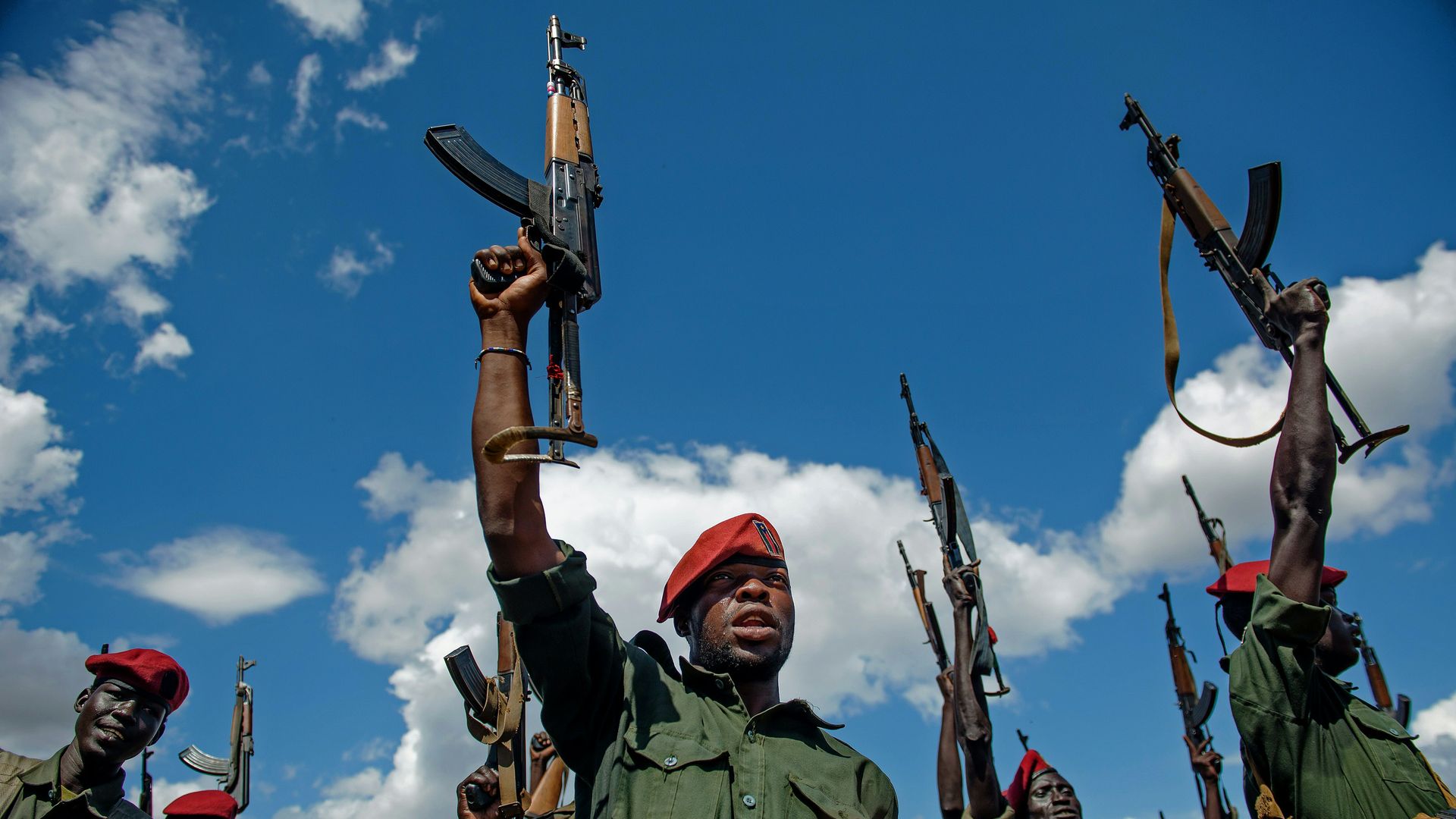 Sudan People's Liberation Army (SPLA) soldiers raise their rifles.