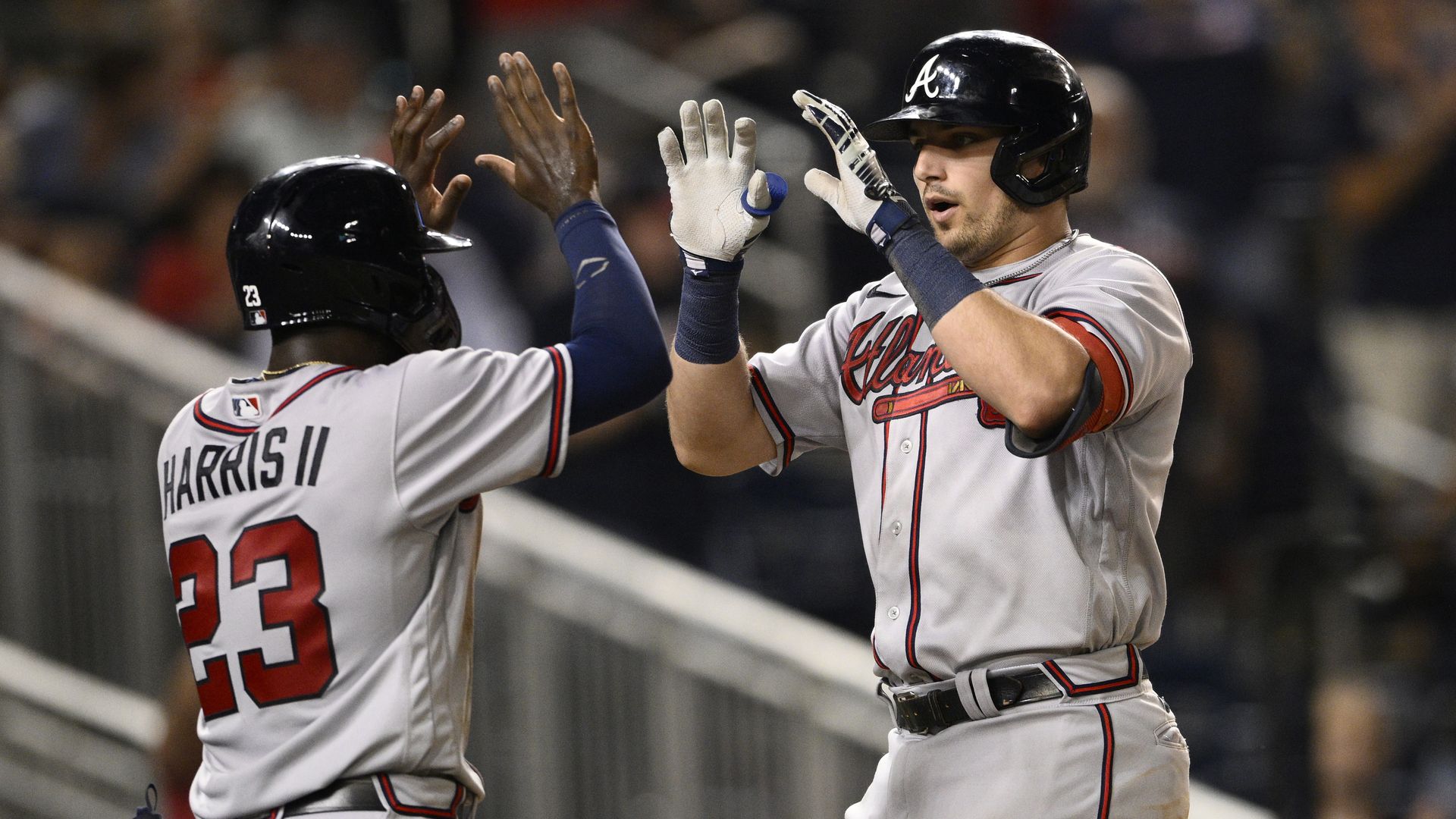 Baseball player Austin Riley of the Braves has two hands up to do a double high-five with teammate Michael Harris II.