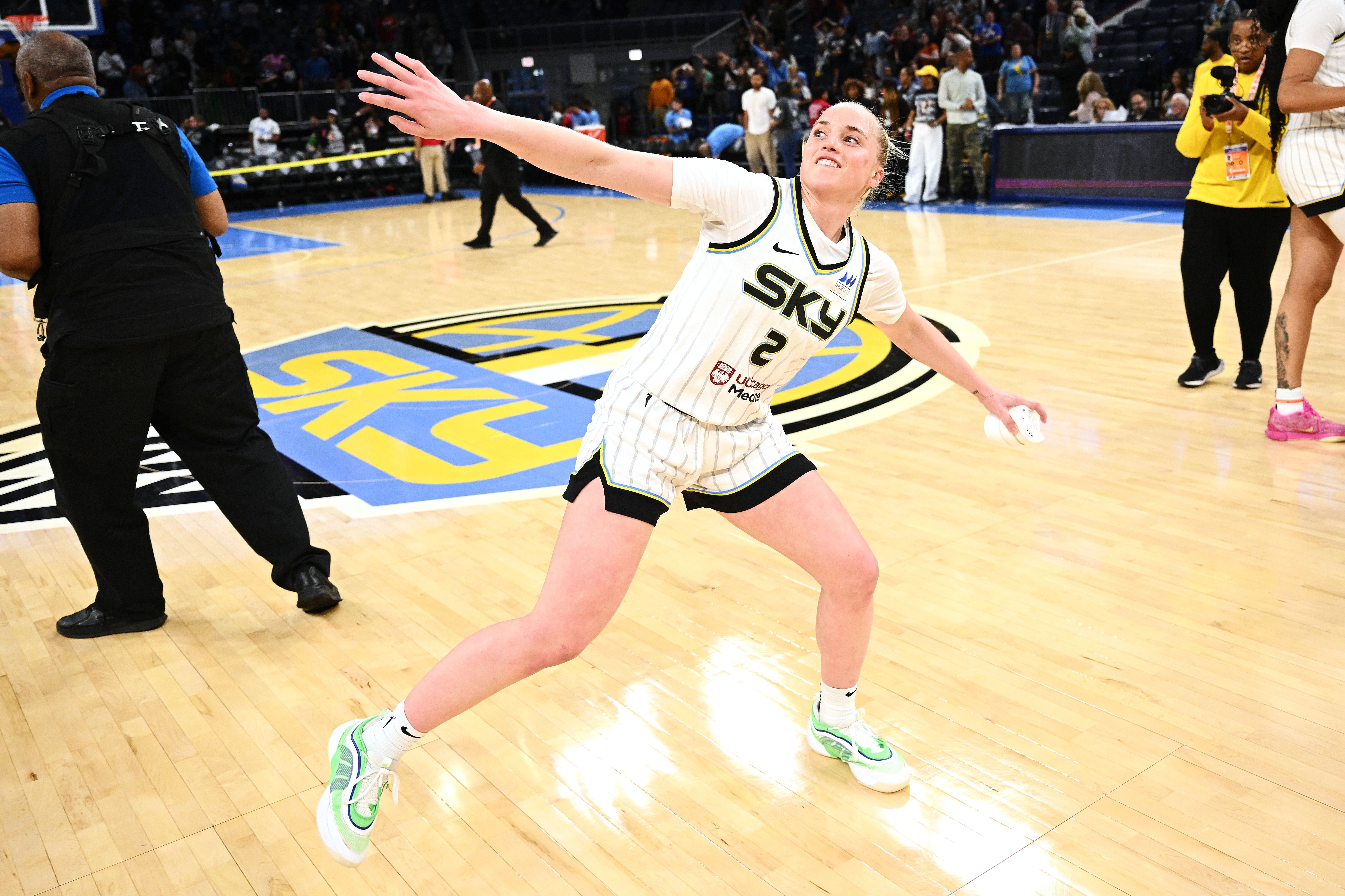 Photo of a player throwing a t-shirt into the stands from a basketball court. 