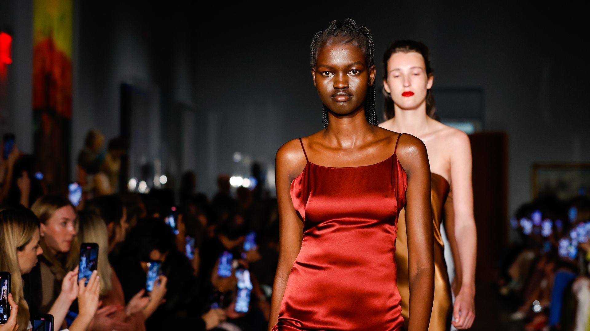 A model walking in an orange dress 