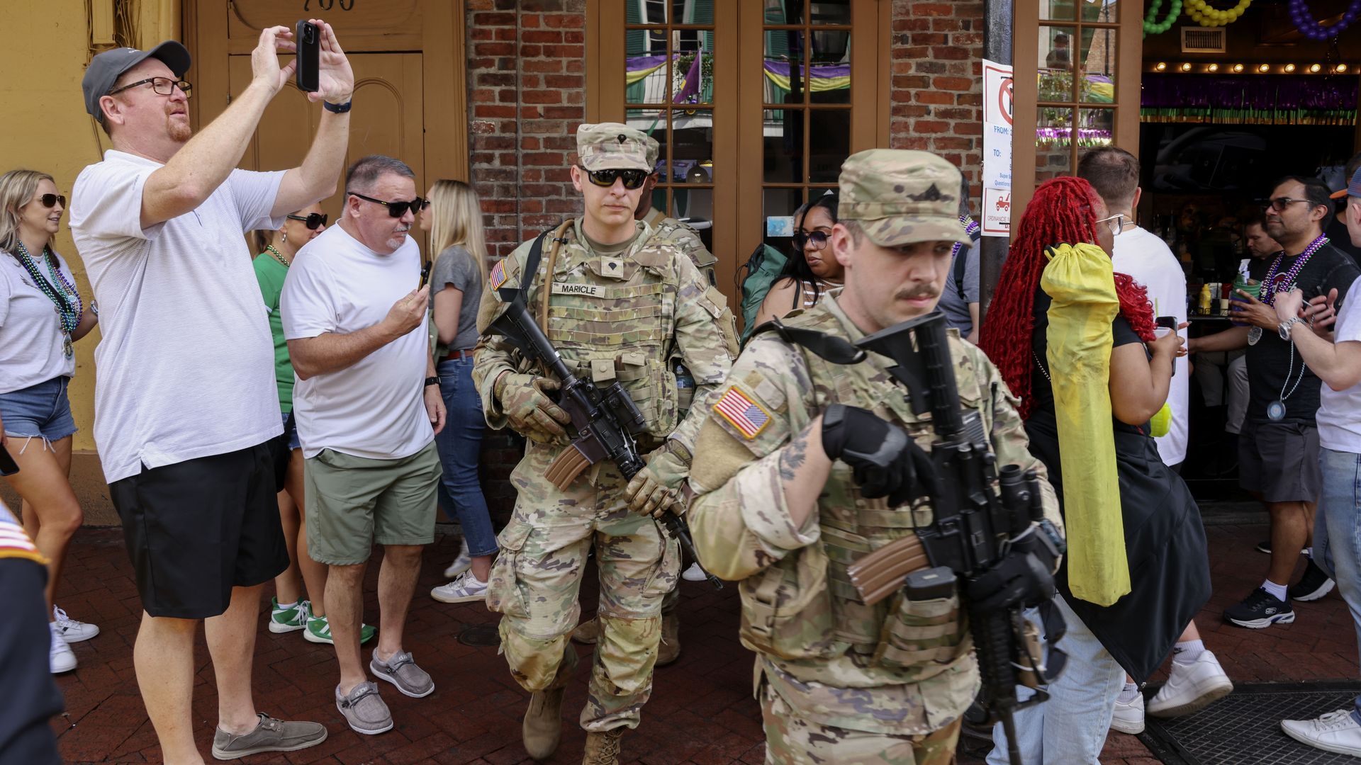 A pair of National Guardsmen navigate through a crowded Bourbon Street sidewalk.