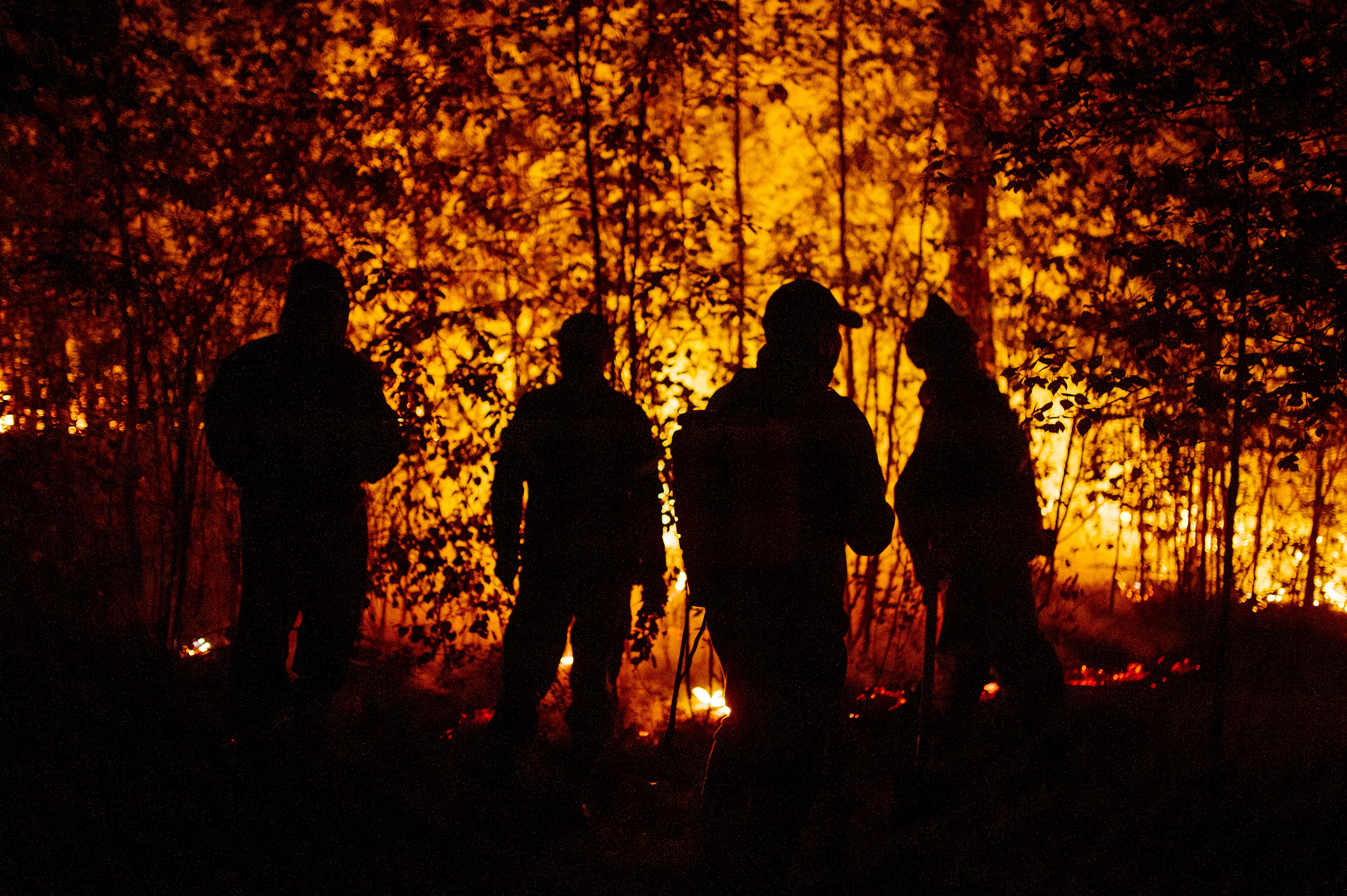 Silhouetted firefighters against a blaze