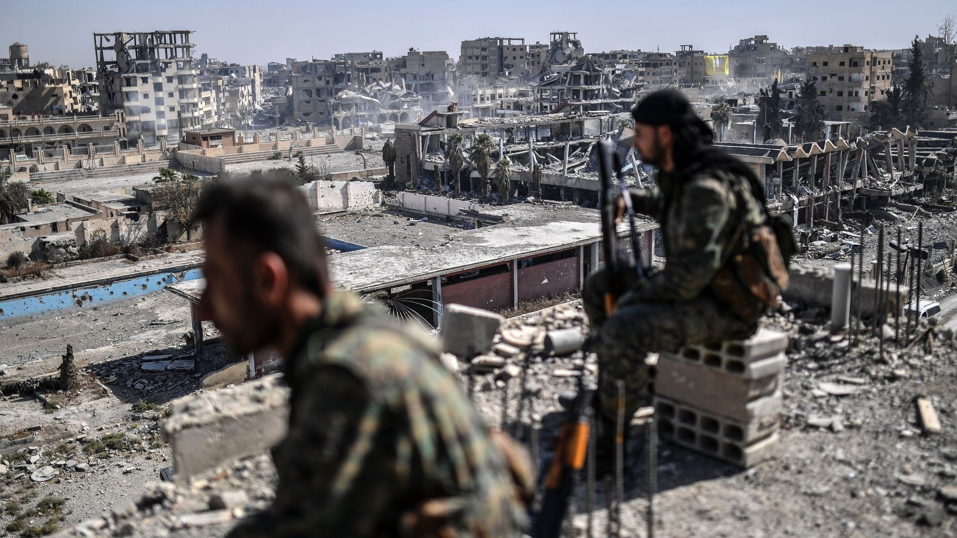 Fighters of the Syrian Democratic Forces (SDF) stand guard on a rooftop in Raqqa.