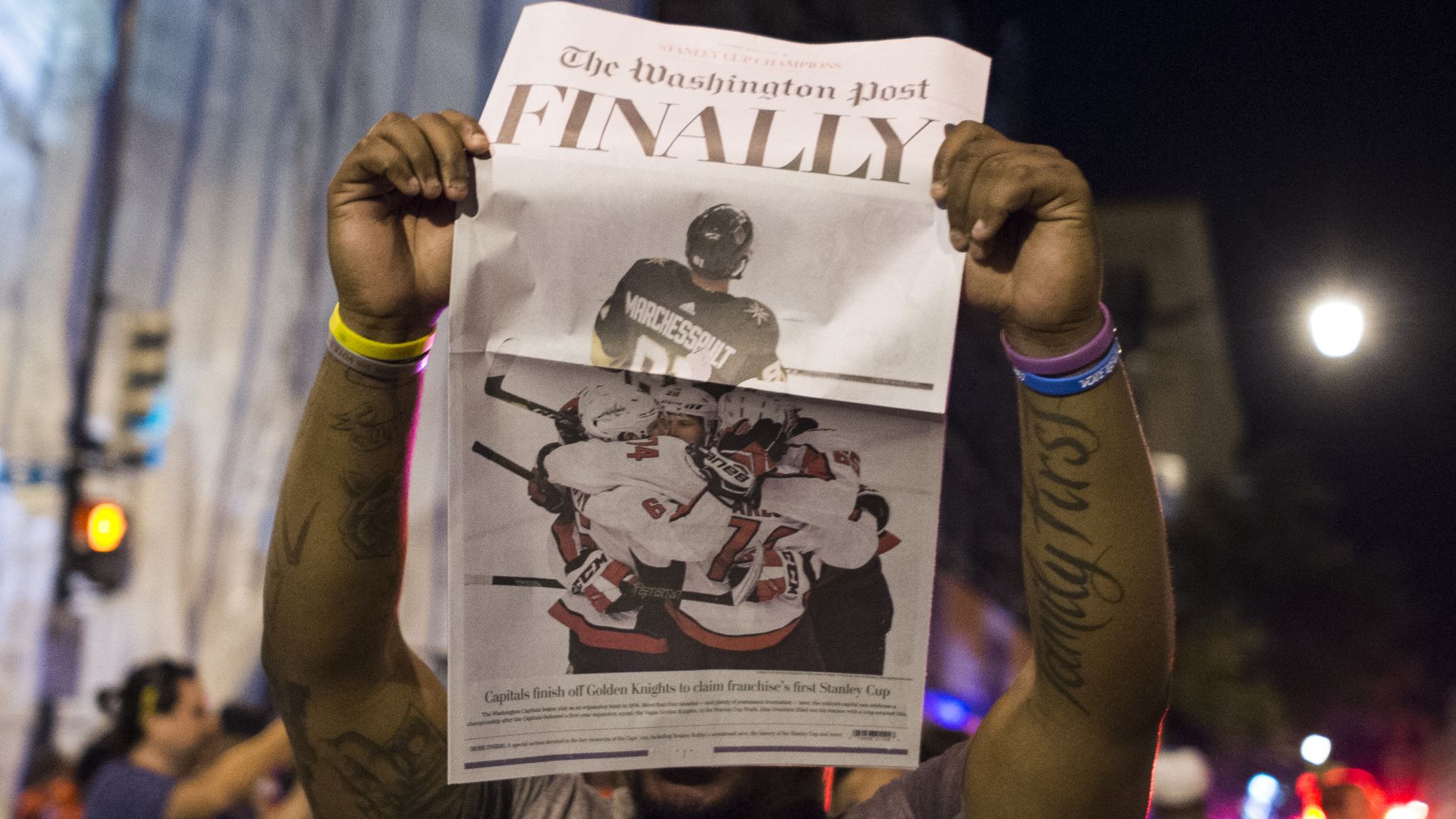 A man holds up a Washington Post front page when the Caps won the Stanley Cup, headline: "FINALLY"