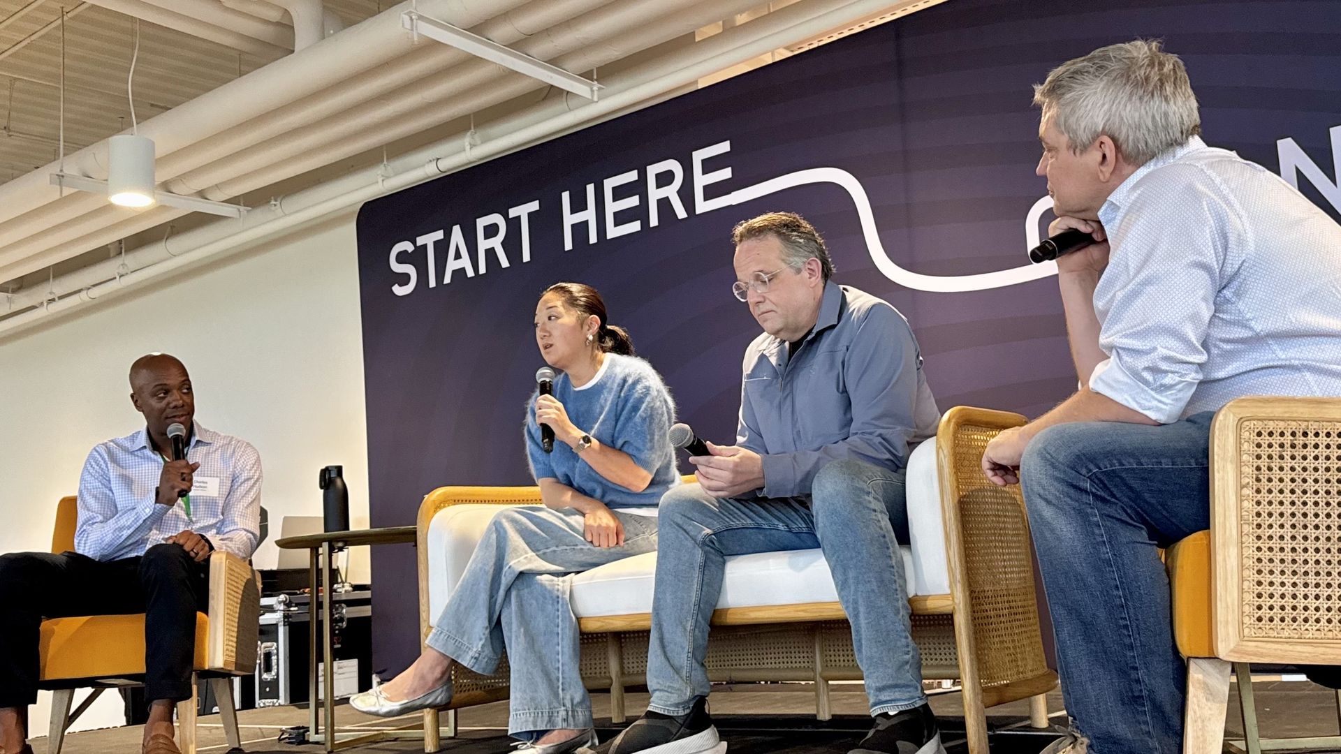 Four people with microphones sit on a stage. 
