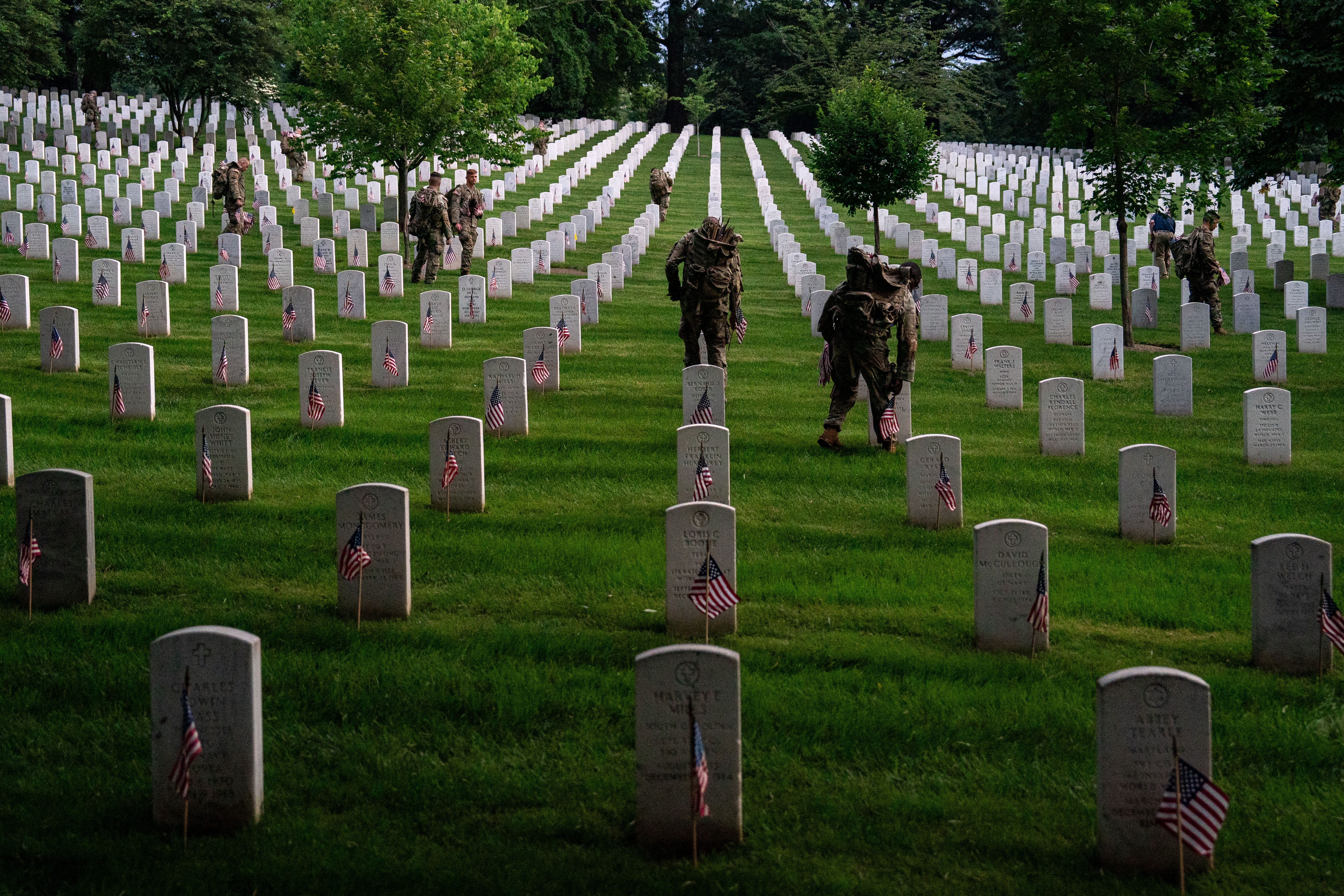 Service members place flags on rows and rows of gravestones