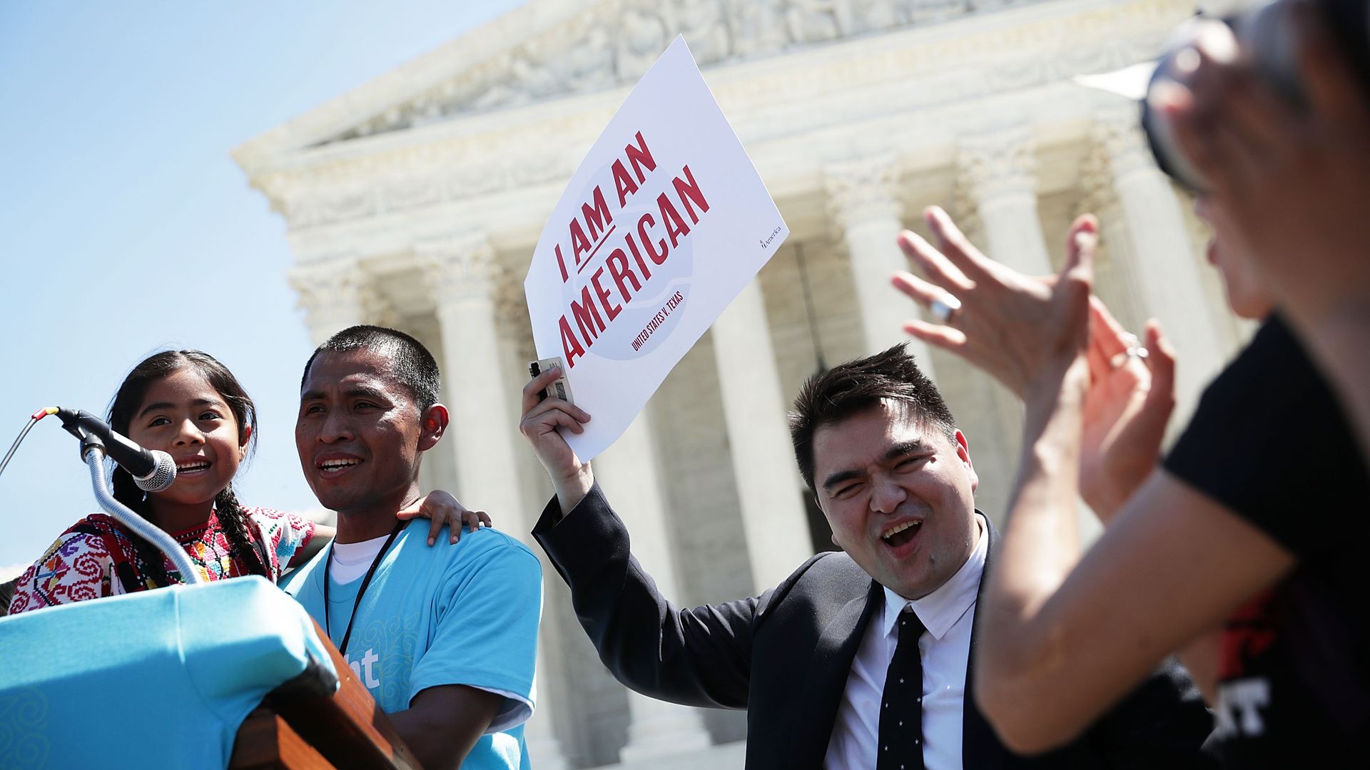 Protestors outside the Supreme Court building with a sign that says "I am an American" 