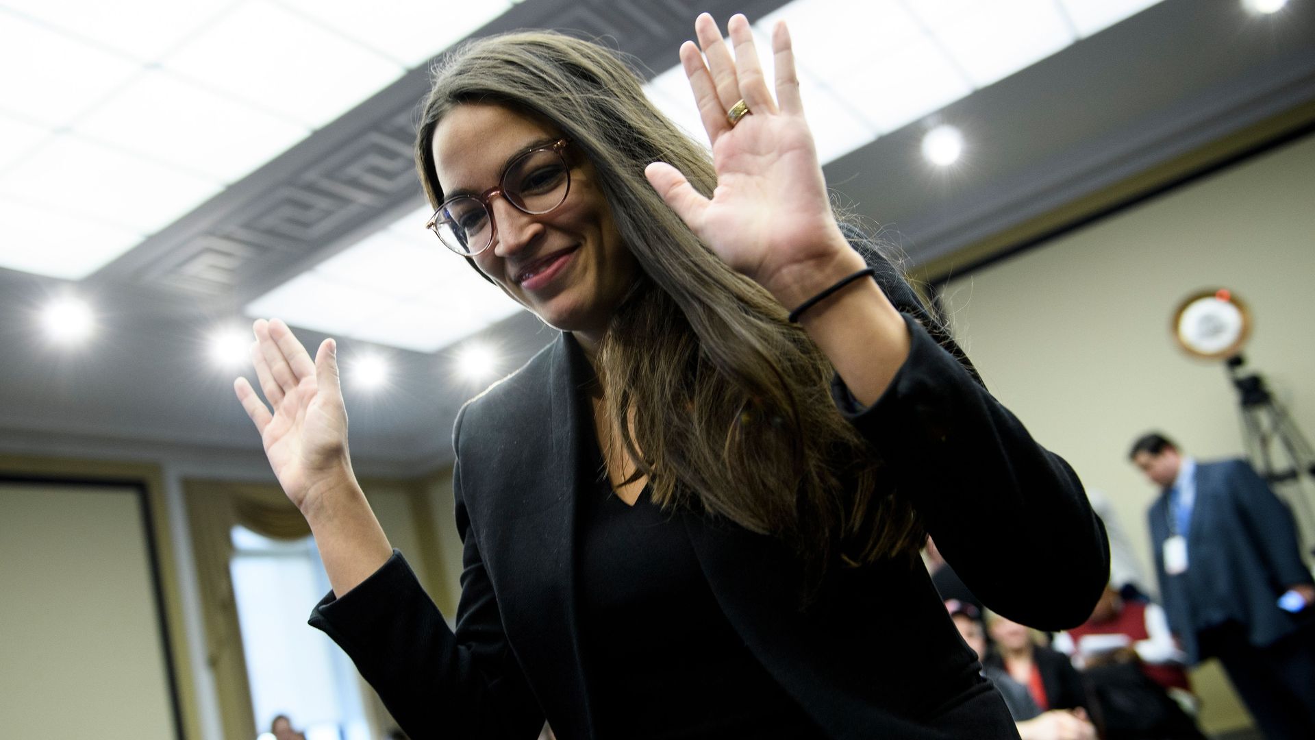 Alexandria ocasio cortez raises her hands. 