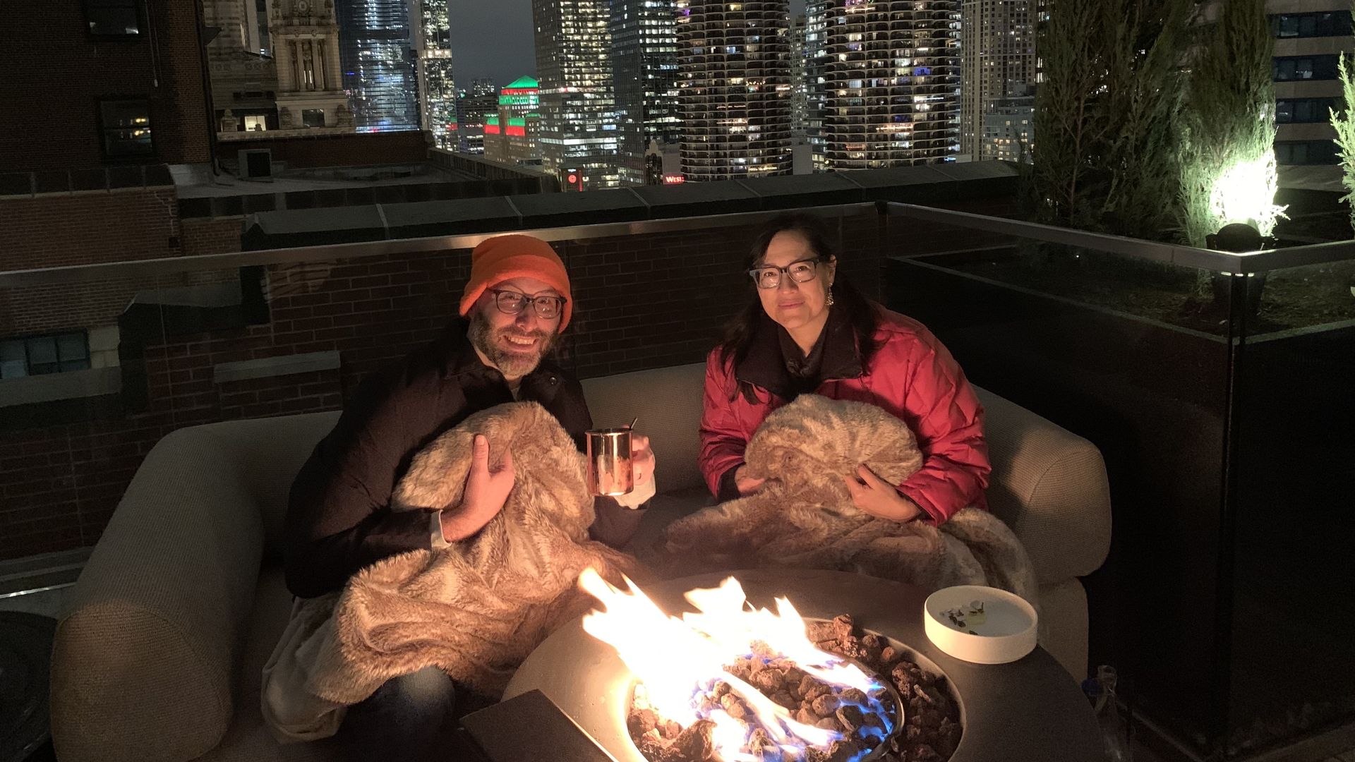 Photo of two people posing for camera in front of a fire pit. 