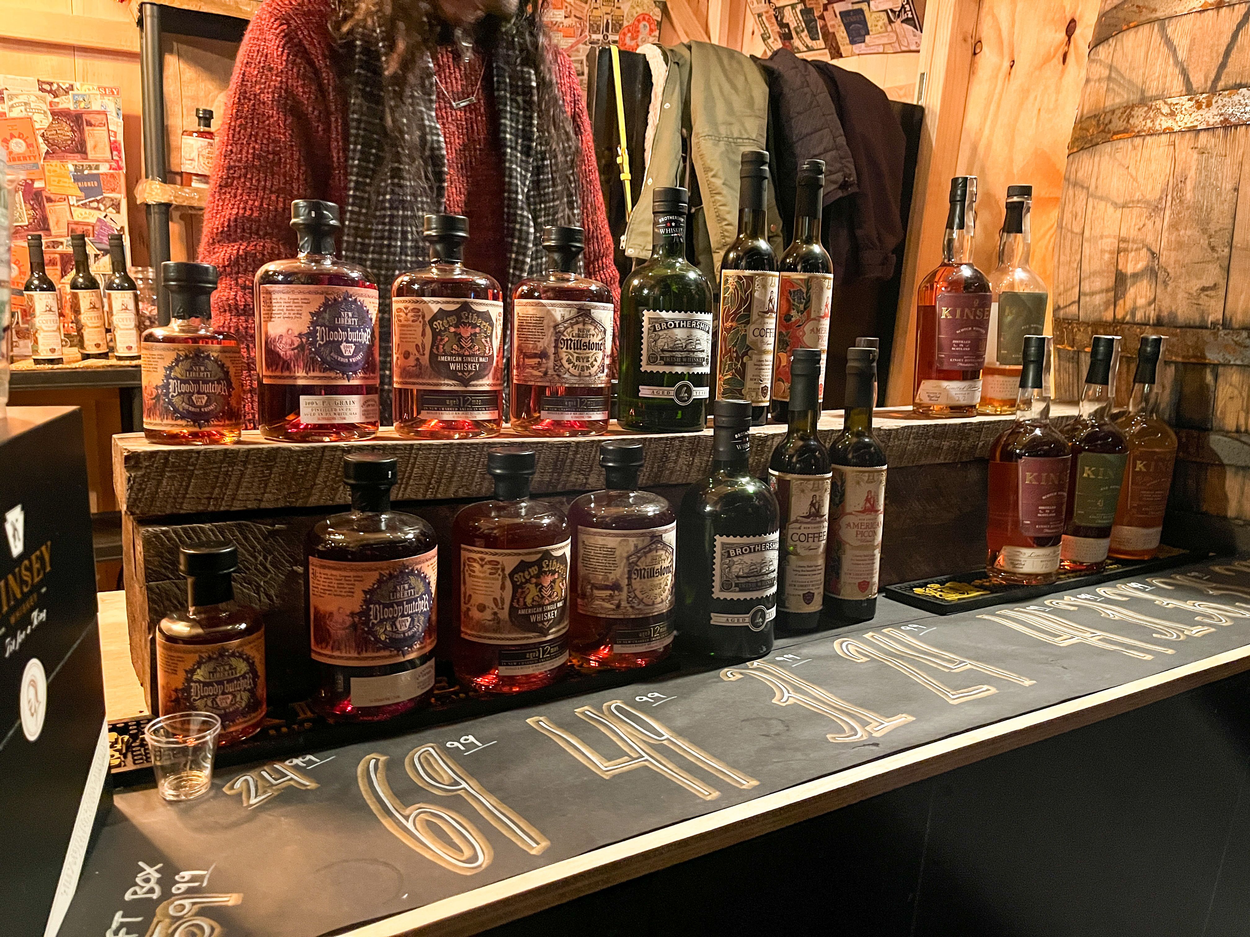 Bottles of New Liberty Distillery's whiskey and aperitifs line a wooden shelf.