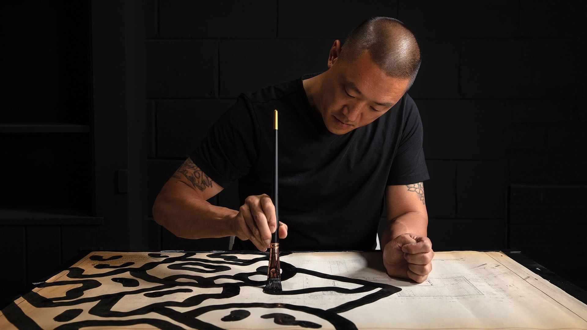 Artist and designer Mike Han holds a paintbrush while working on a piece