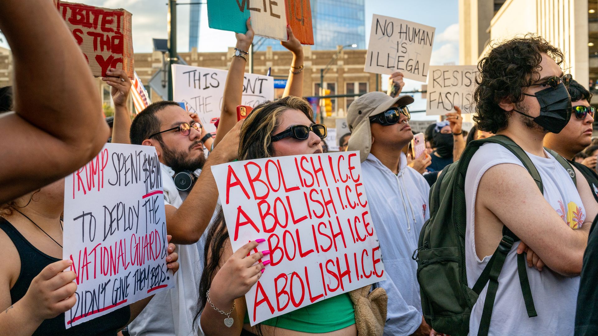 People protest against U.S. Immigration and Customs Enforcement (ICE) raids at San Antonio City Hall on June 11, 2025 in San Antonio. One sign reads "Abolish ICE" in red text four times.