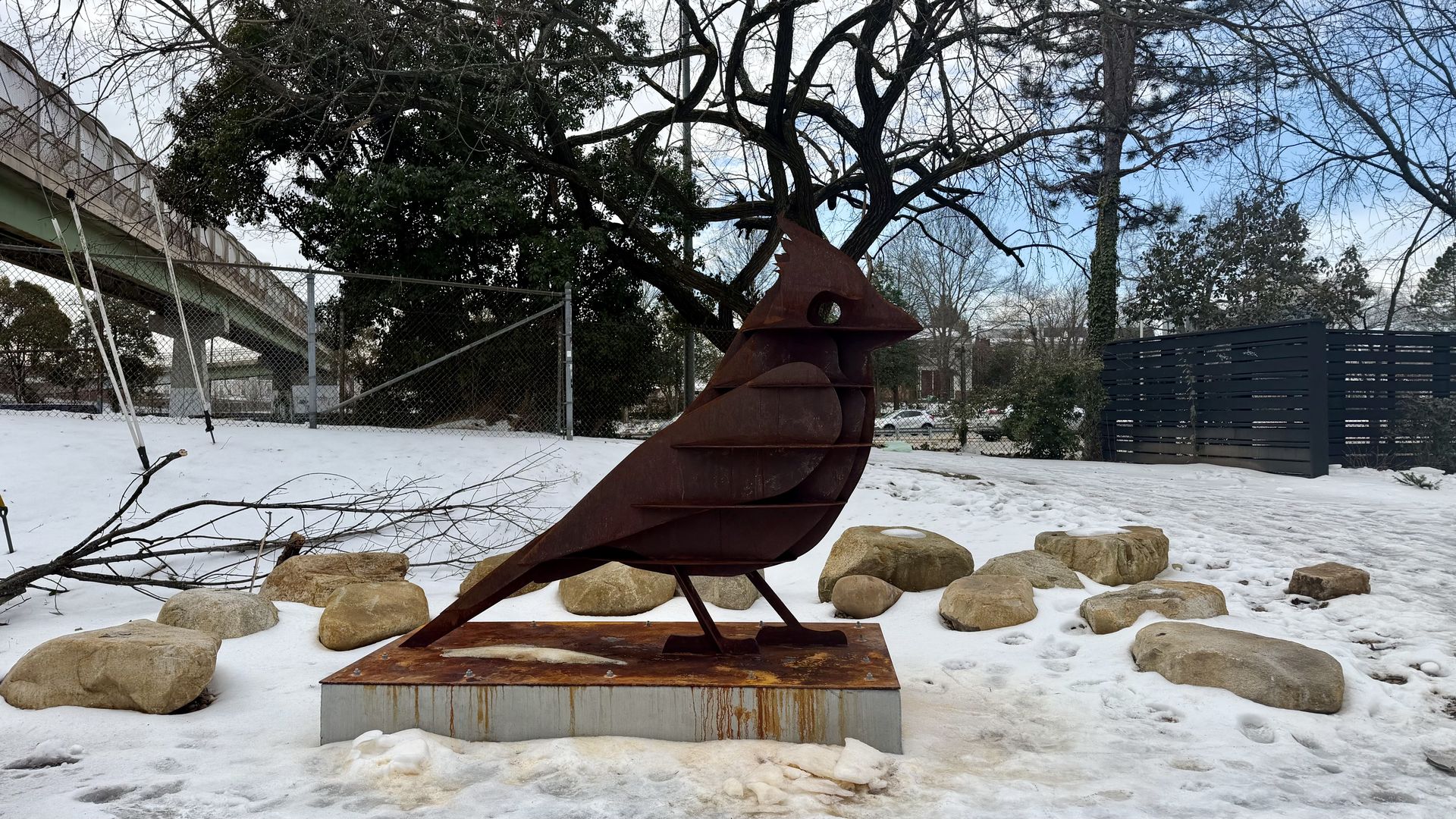 A metal bird surrounded by snow and ice and rocks 