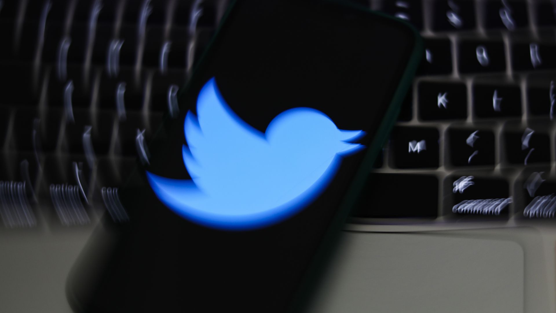 Photo illustration of a blurred Twitter logo on someone's phone