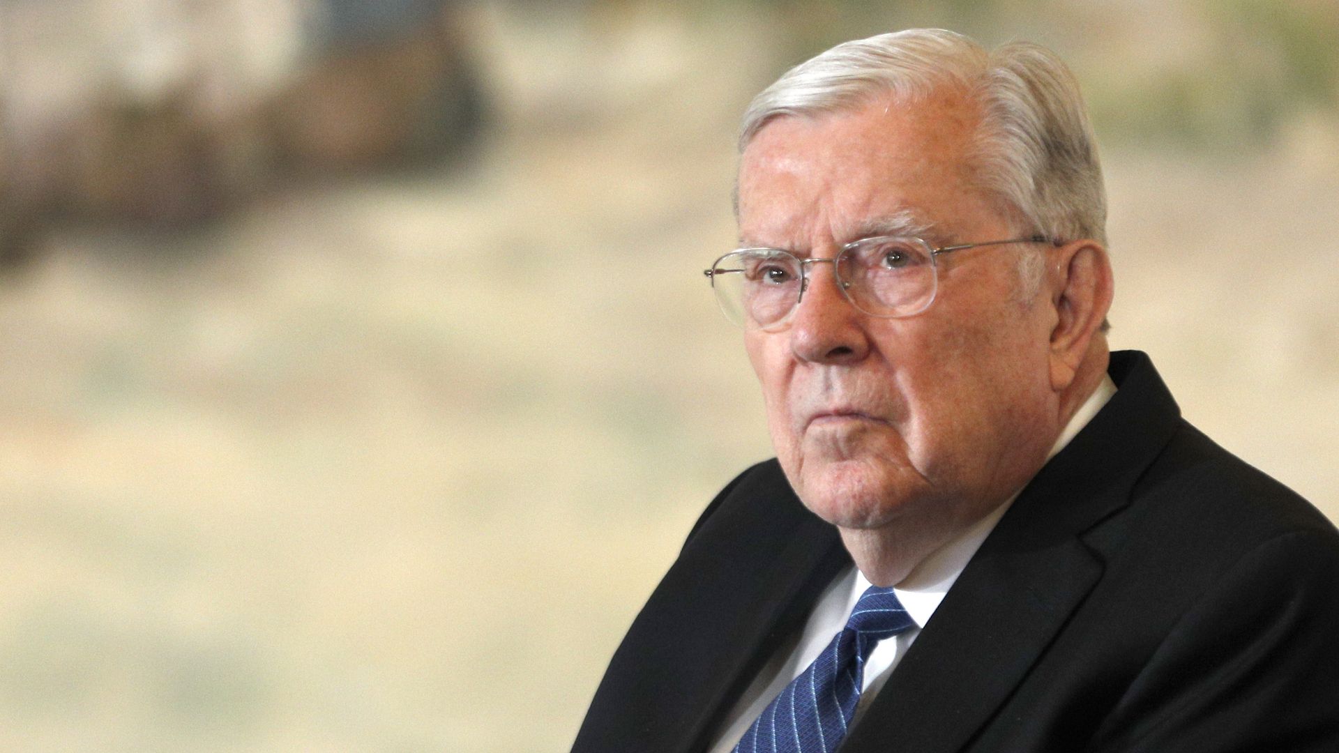 M. Russell Ballard sits in a dark suit and blue striped tie