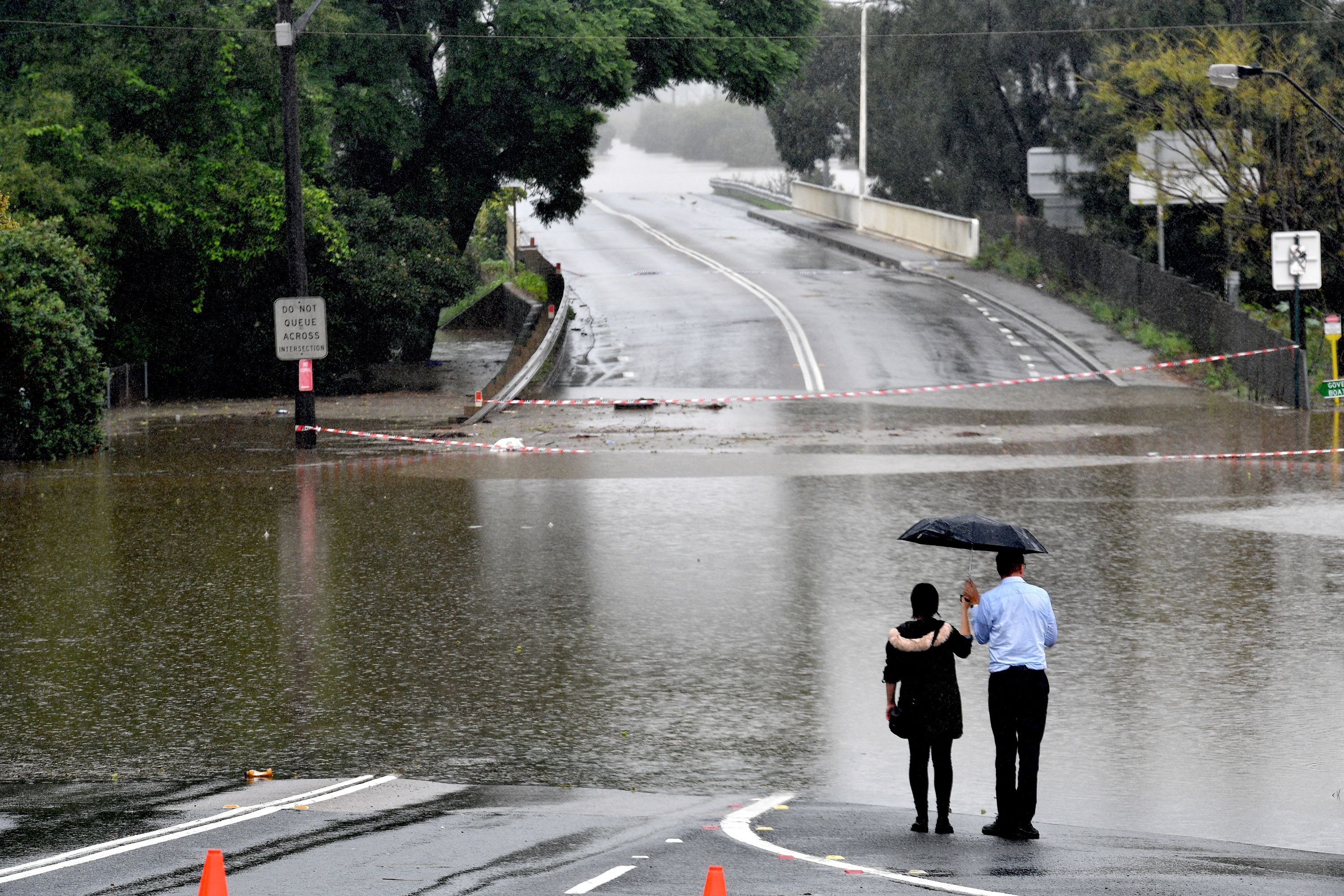  People look out at a flooded residential area in the Windsor area in northwestern Sydney on March 23